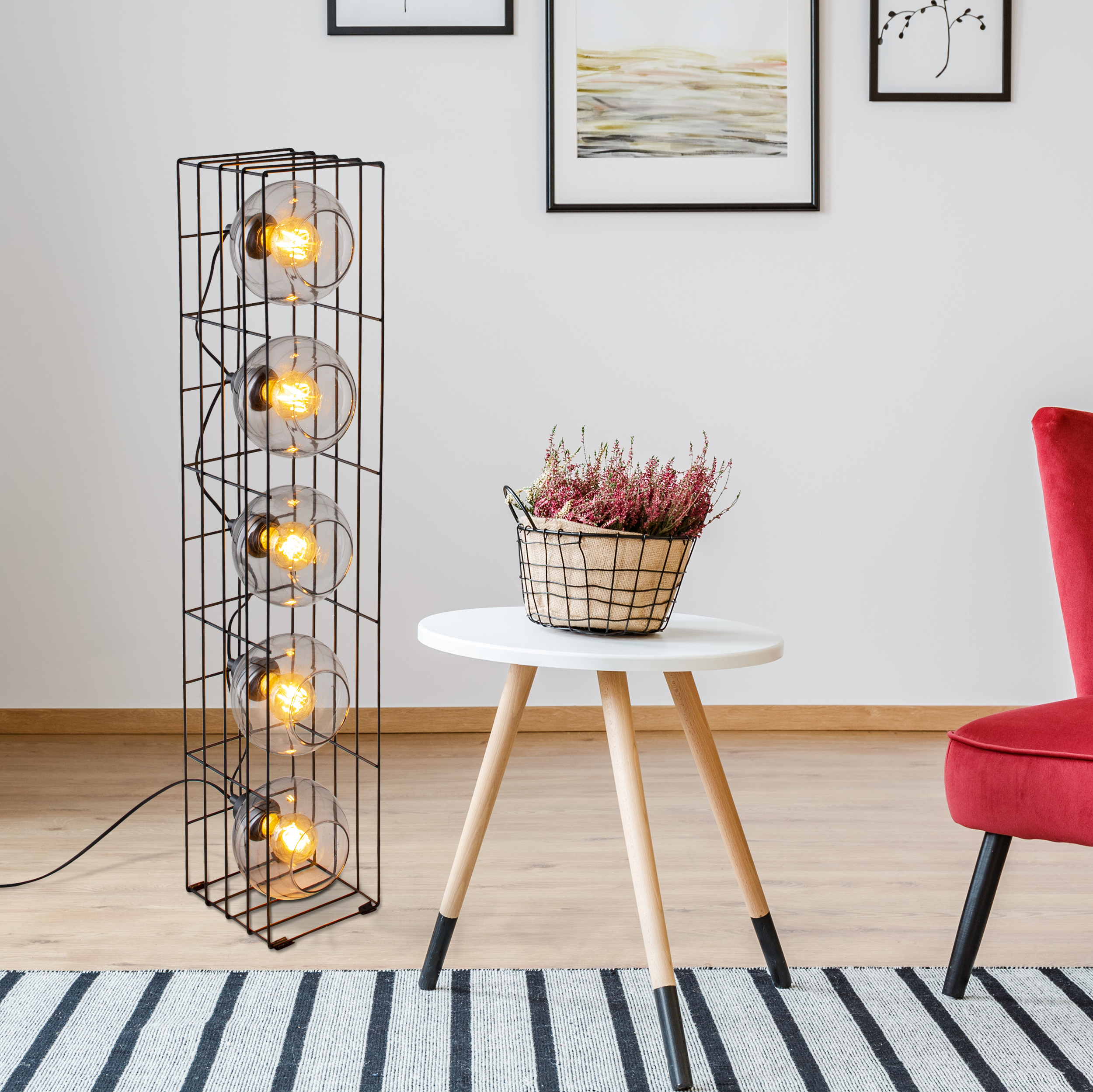 Schwarze Metalllampe mit Glaskugeln, Beistelltisch mit Pflanze und roter Stuhl.