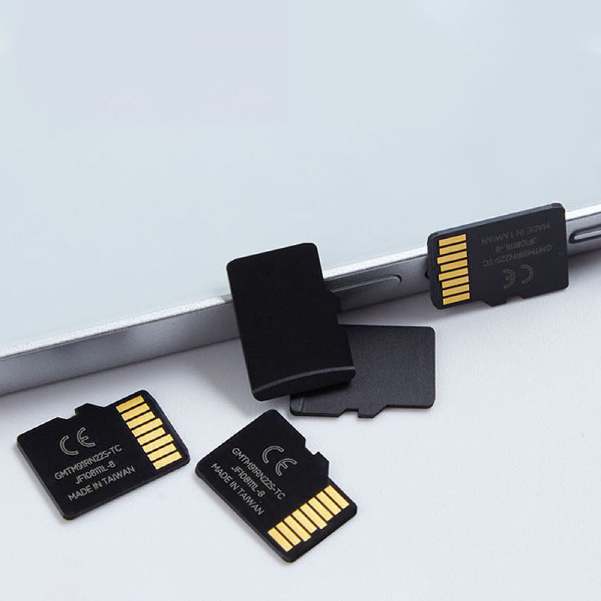 Karty SD i karty micro SD na białej powierzchni. Niektóre karty są na telefonie.