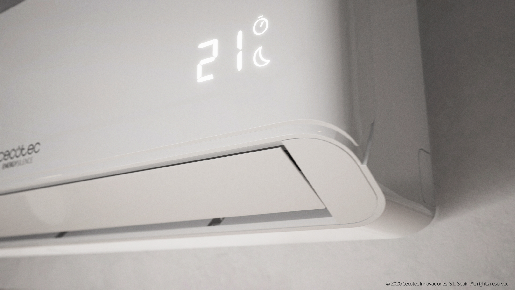 Il condizionatore bianco mostra 21 gradi. È montato su un muro bianco.