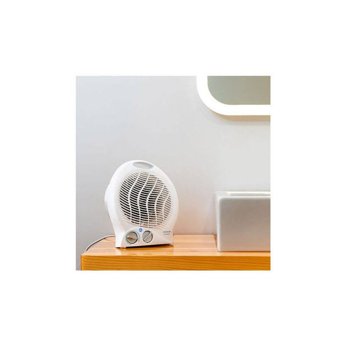 Biały wentylator na drewnianym stole. W tle lustro i umywalka. Biała ściana.