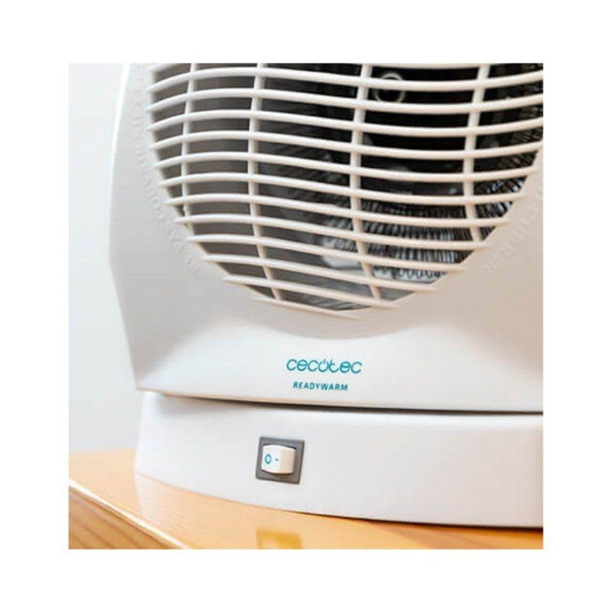 Biały grzejnik Cecotec Readywarm. Przycisk zasilania jest włączony, a wentylator jest widoczny. Białe tło.