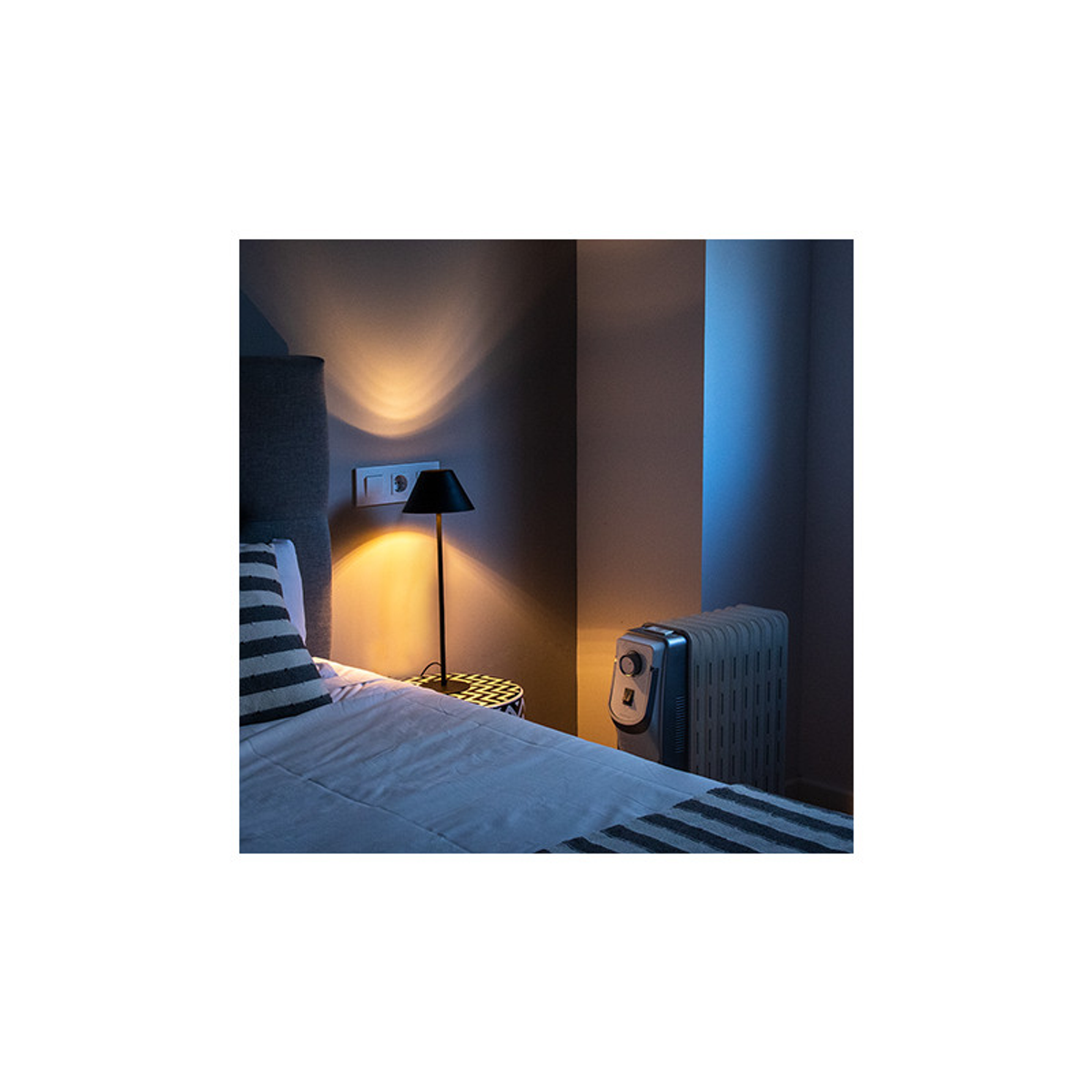 Scena sypialni w nocy, z lampą i grzejnikiem zapewniającymi światło i ciepło.