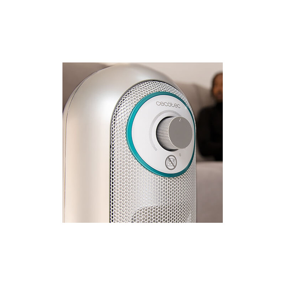 Zbliżenie na srebrno-biały grzejnik. Osoba jest rozmyta w tle.