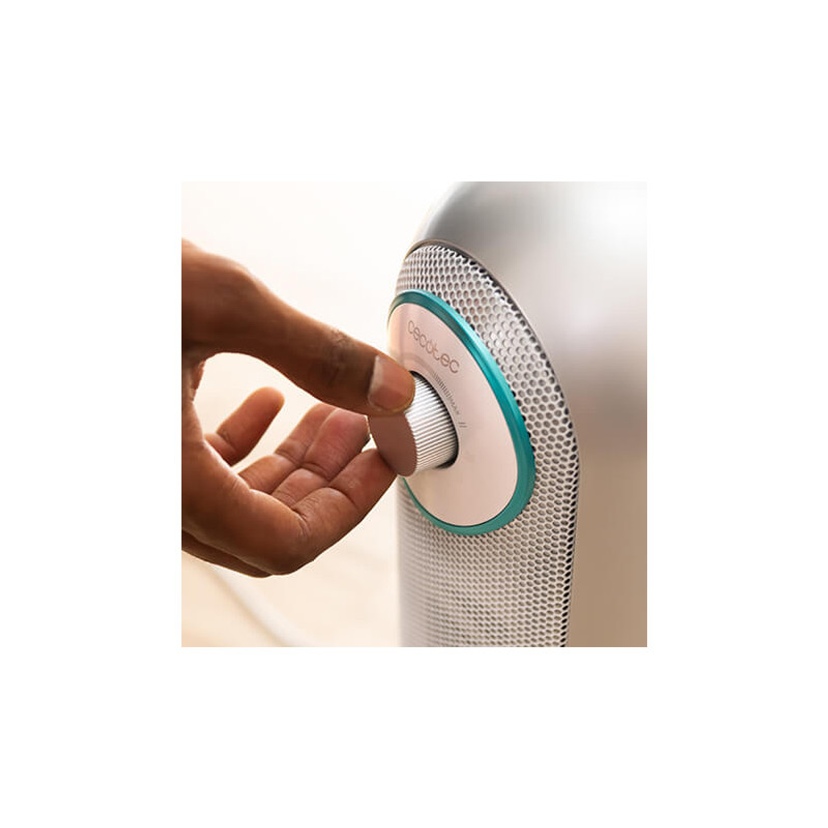 Dłoń obracająca pokrętło na srebrno-turkusowym urządzeniu.