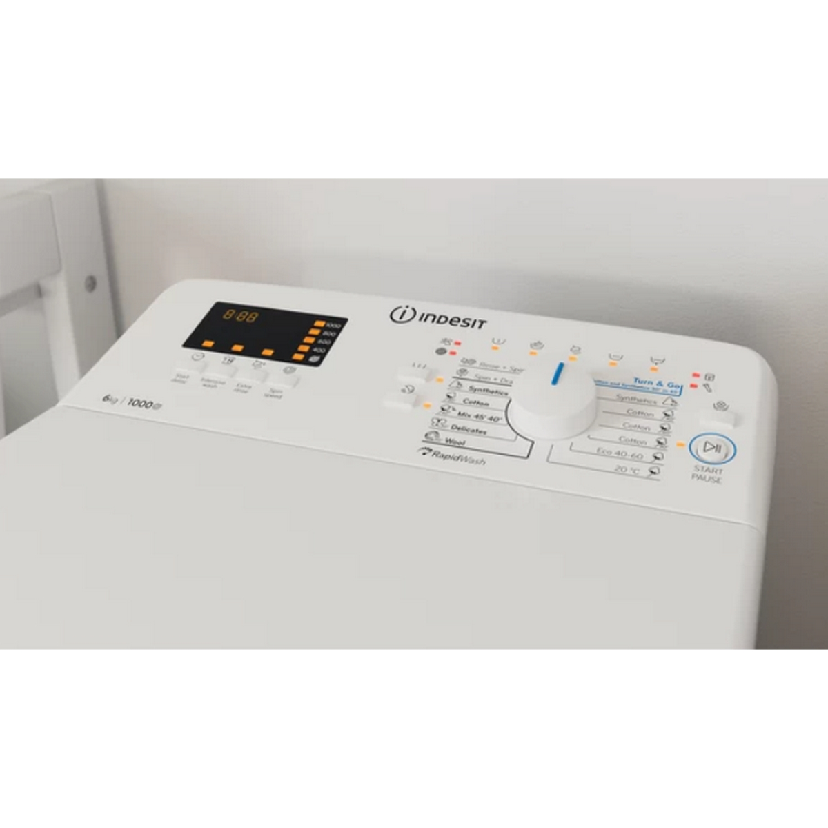 Primo piano del pannello di controllo di una lavatrice Indesit bianca. Pulsanti, quadrante e display visibili.