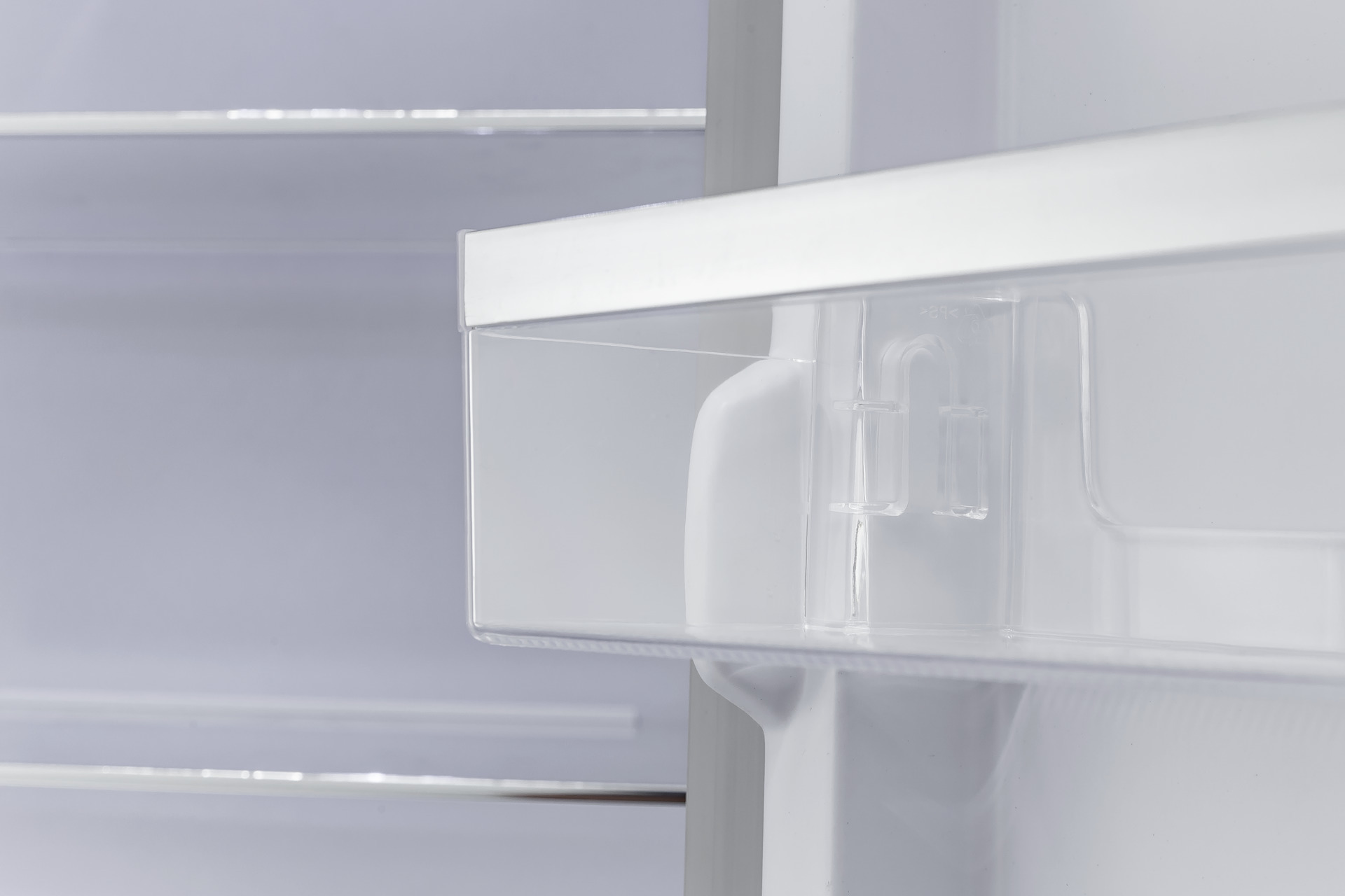 Dentro de un refrigerador. Estante de plástico transparente con soporte. Interior blanco y gris.