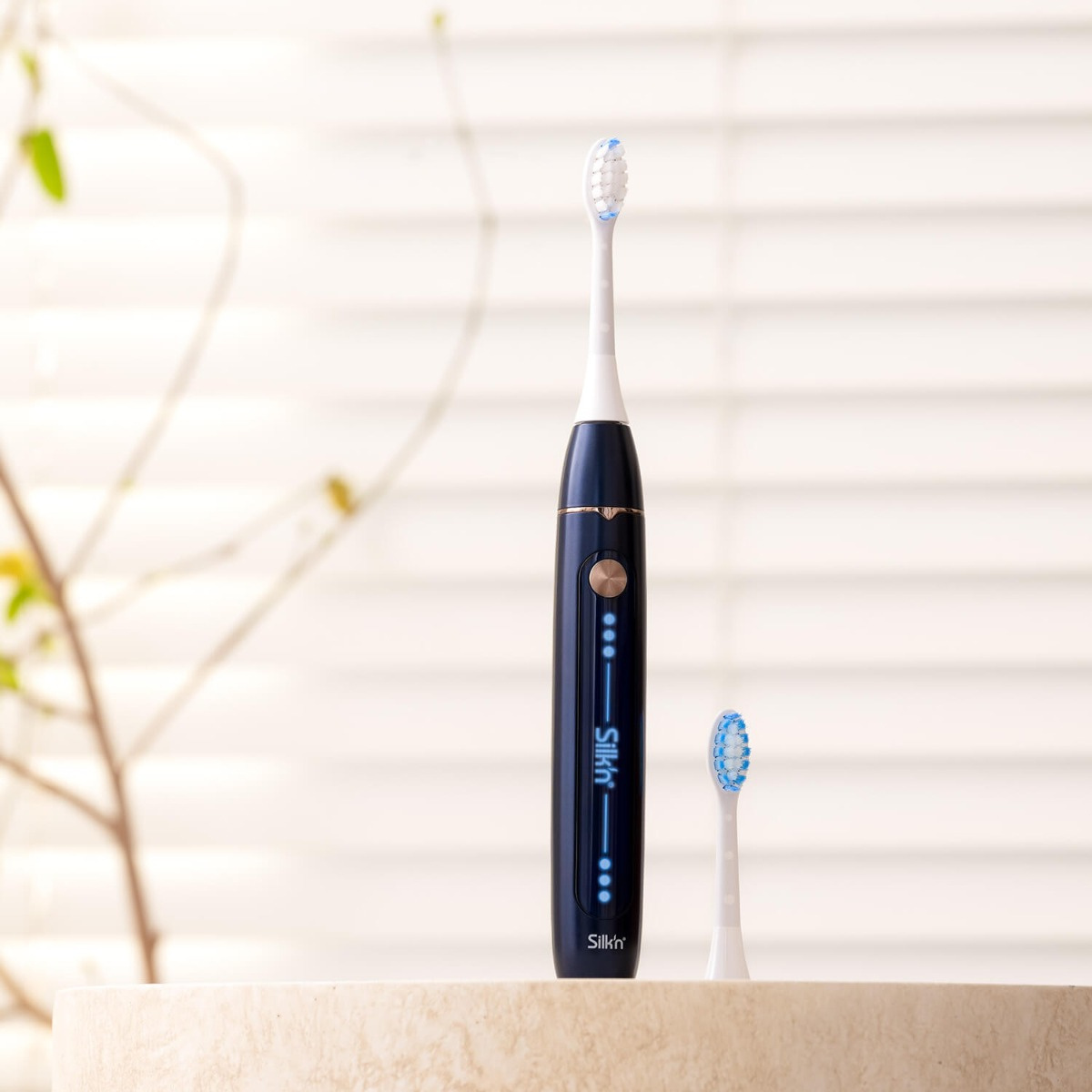 Blaue und schwarze elektrische Zahnbürste mit zusätzlichem Kopf, auf Tisch.