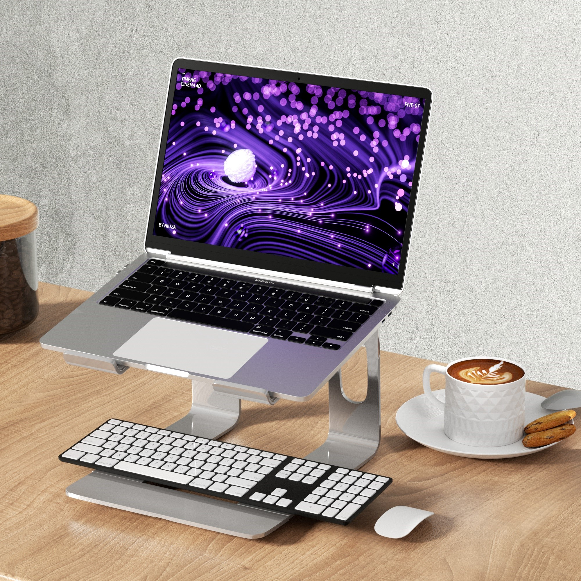 Laptop auf einem Ständer mit Tastatur und Maus. Eine Tasse Kaffee und ein Glas Kaffeebohnen daneben.