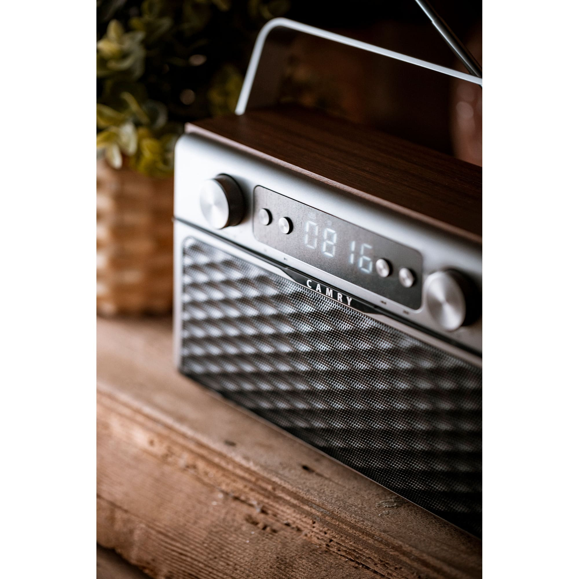 A wooden radio with a digital clock display and a speaker, placed on a wooden surface.