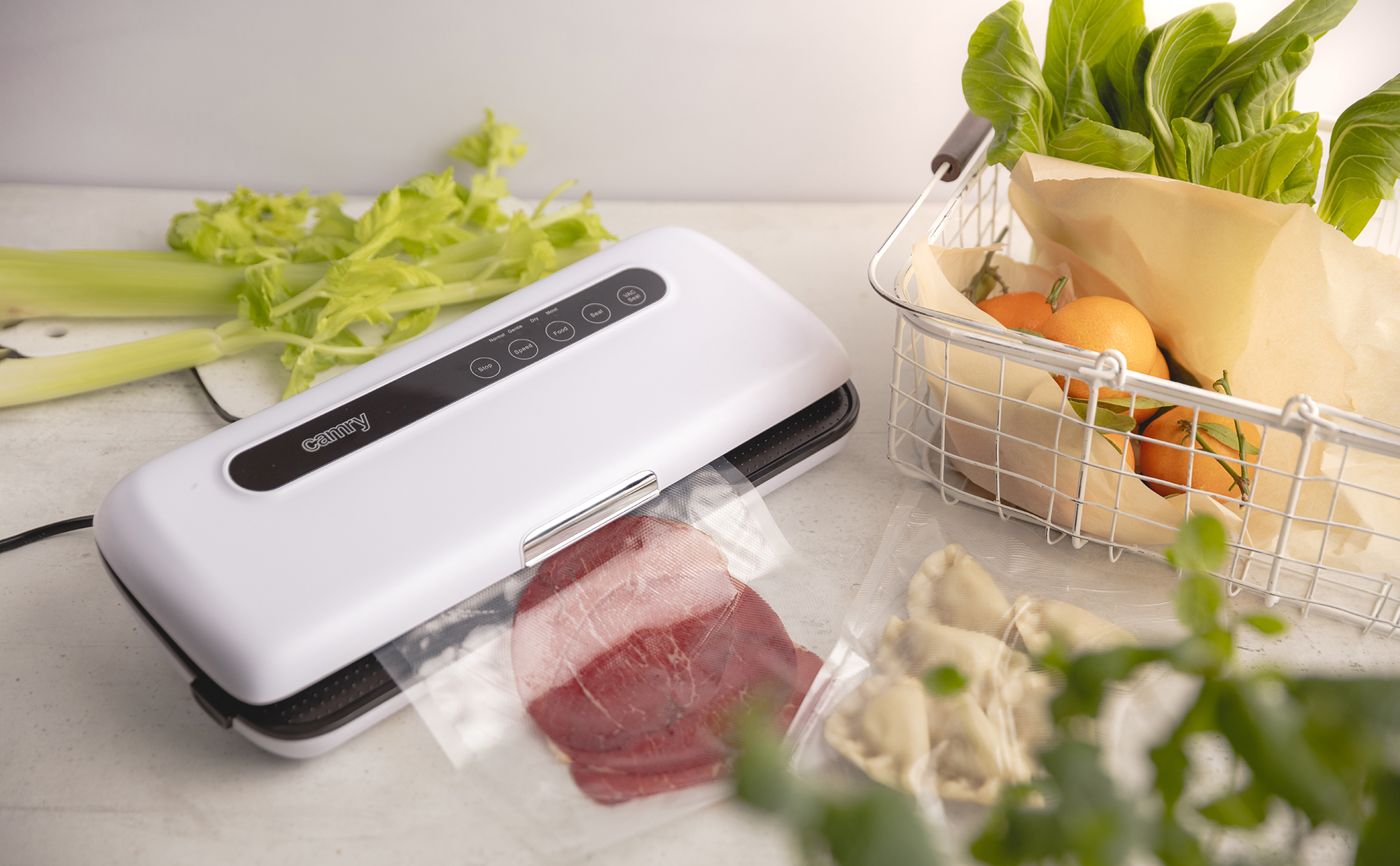 Zgrzewarka próżniowa, warzywa i woreczki z żywnością na białej powierzchni.