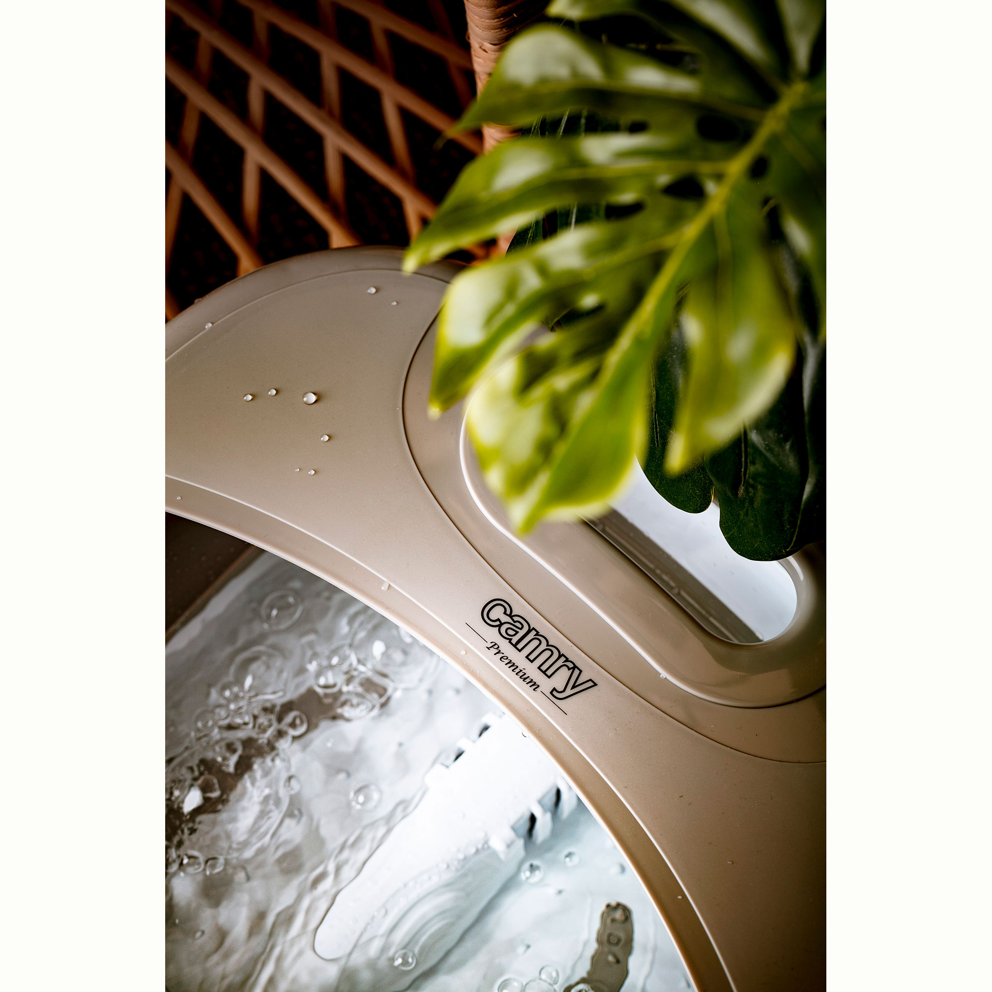 Spa per piedi con acqua, foglie e logo Camy. Sfondo in vimini visibile.