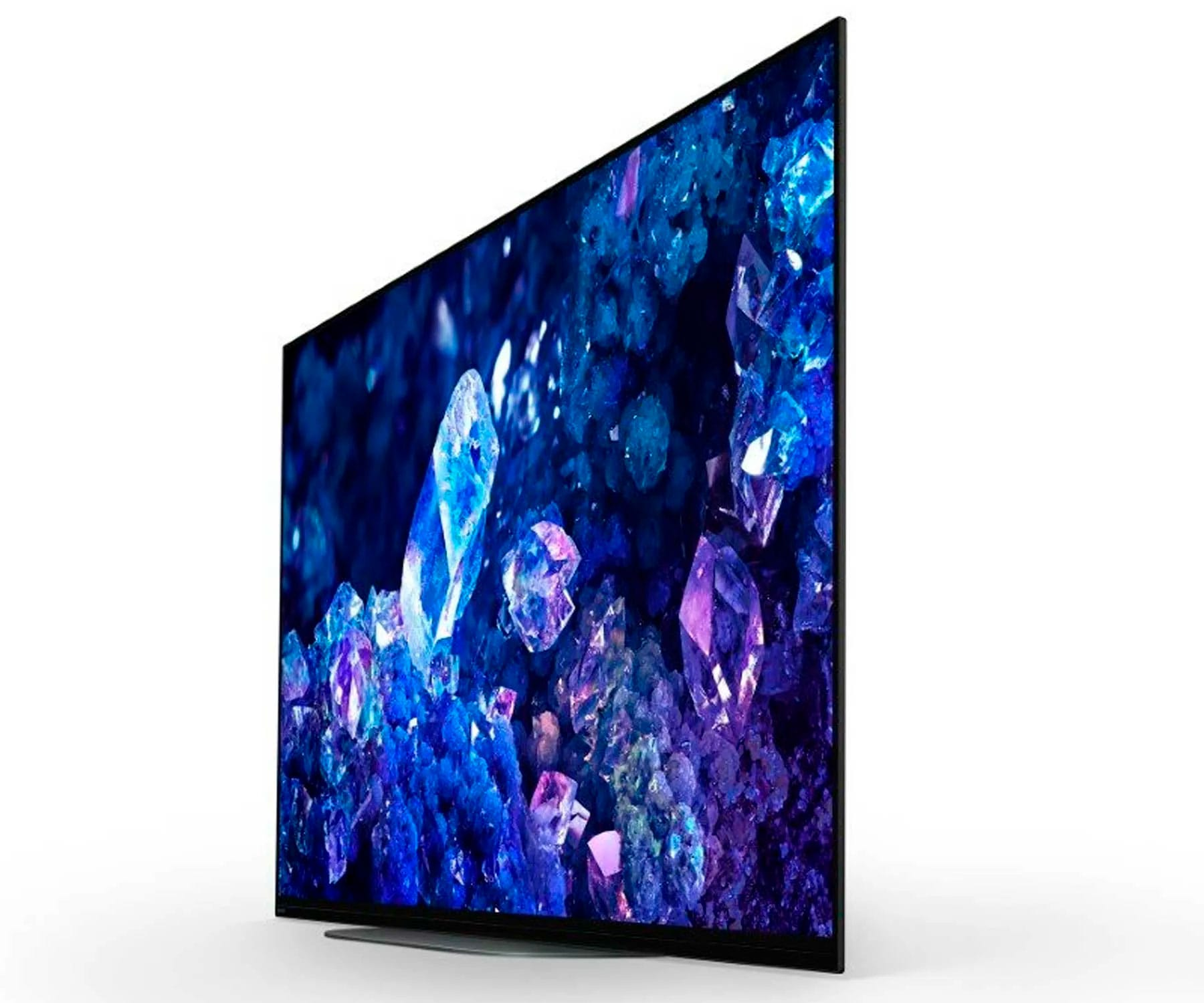Uno schermo TV inclinato che mostra formazioni di cristalli astratti e colorati su uno sfondo blu scuro.