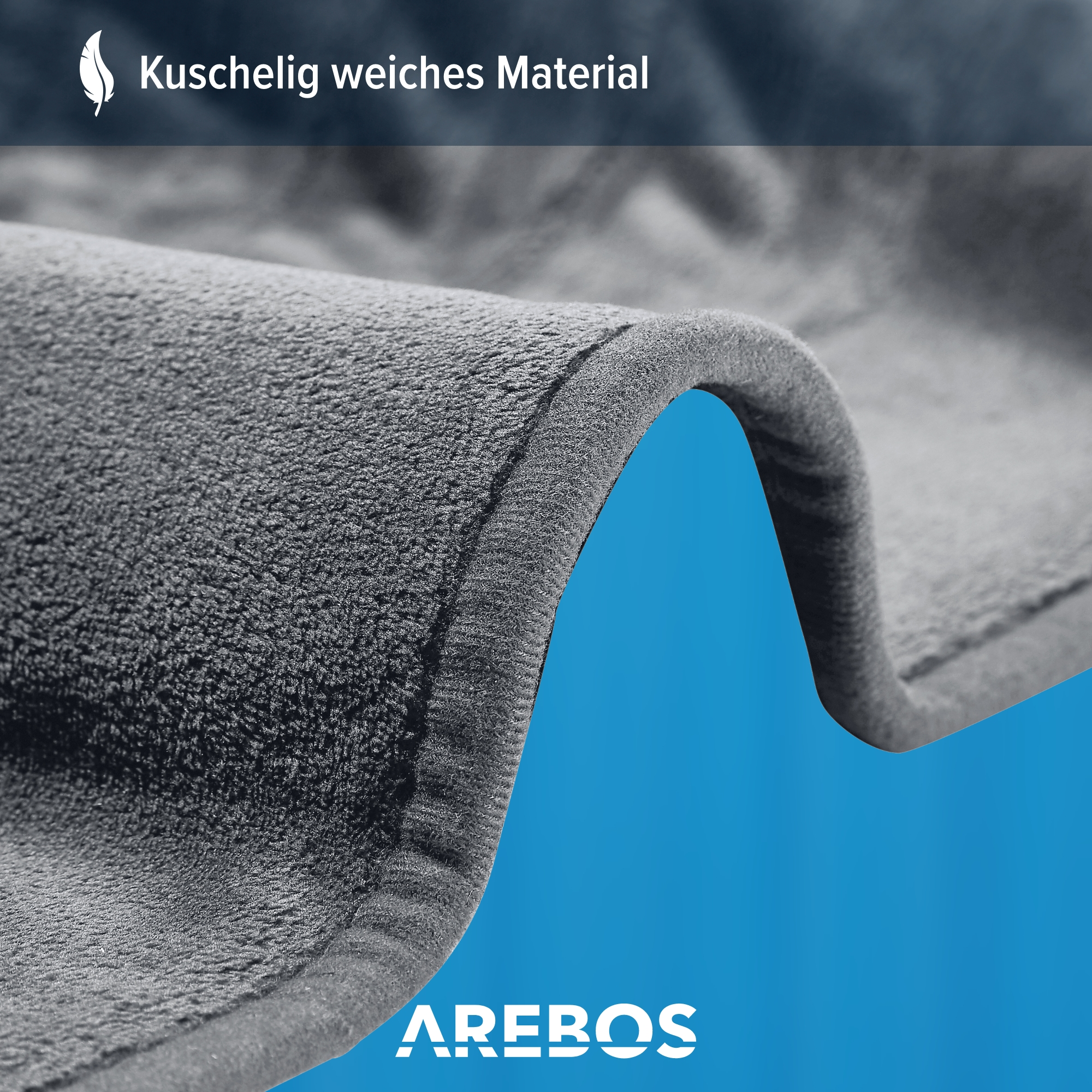 Nahaufnahme einer grauen, weichen Decke. Der Text 'Kuschelig weiches Material' steht oben.