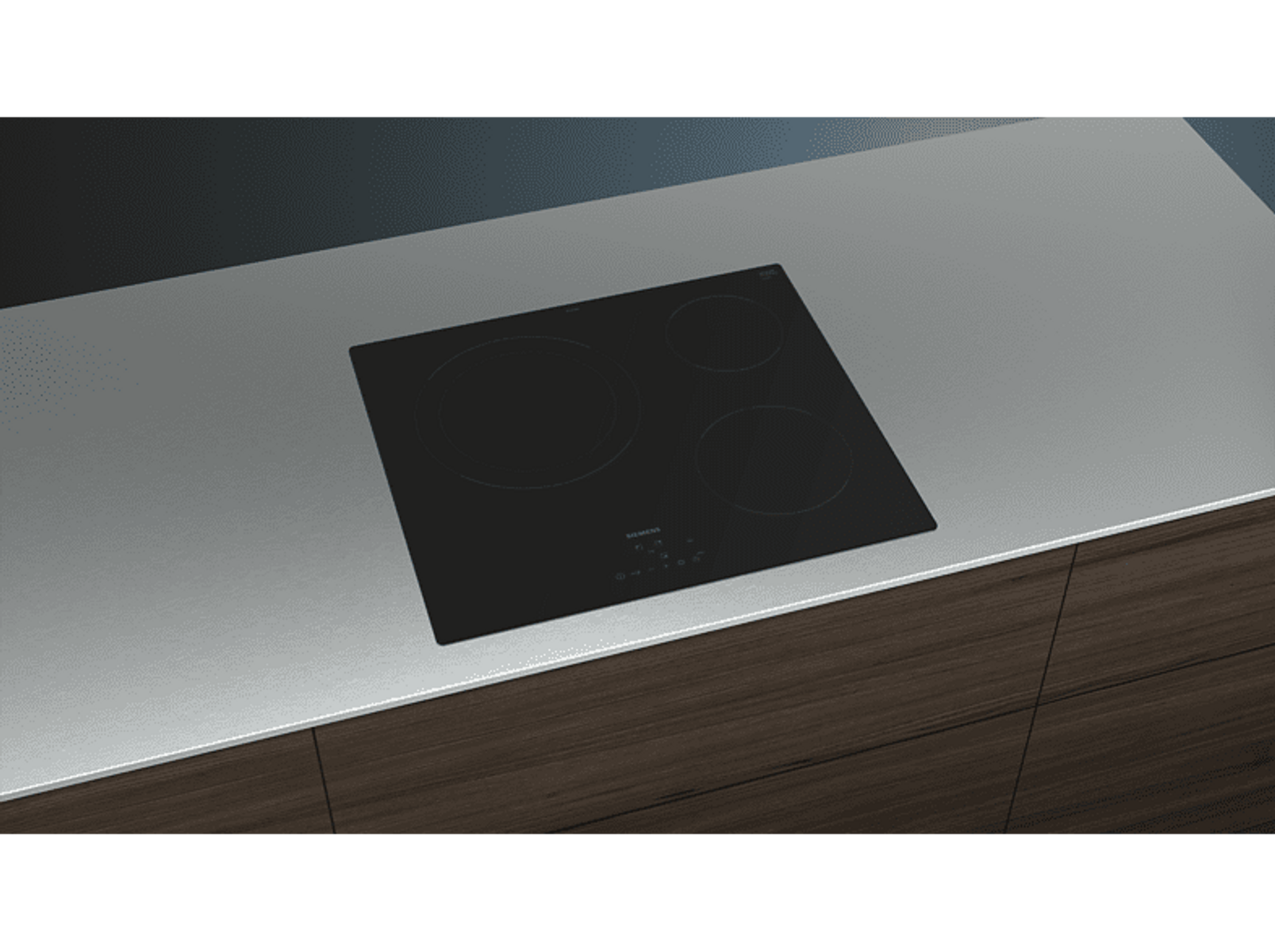 Czarna płyta indukcyjna na szarym blacie. Drewniana szafka pod spodem.