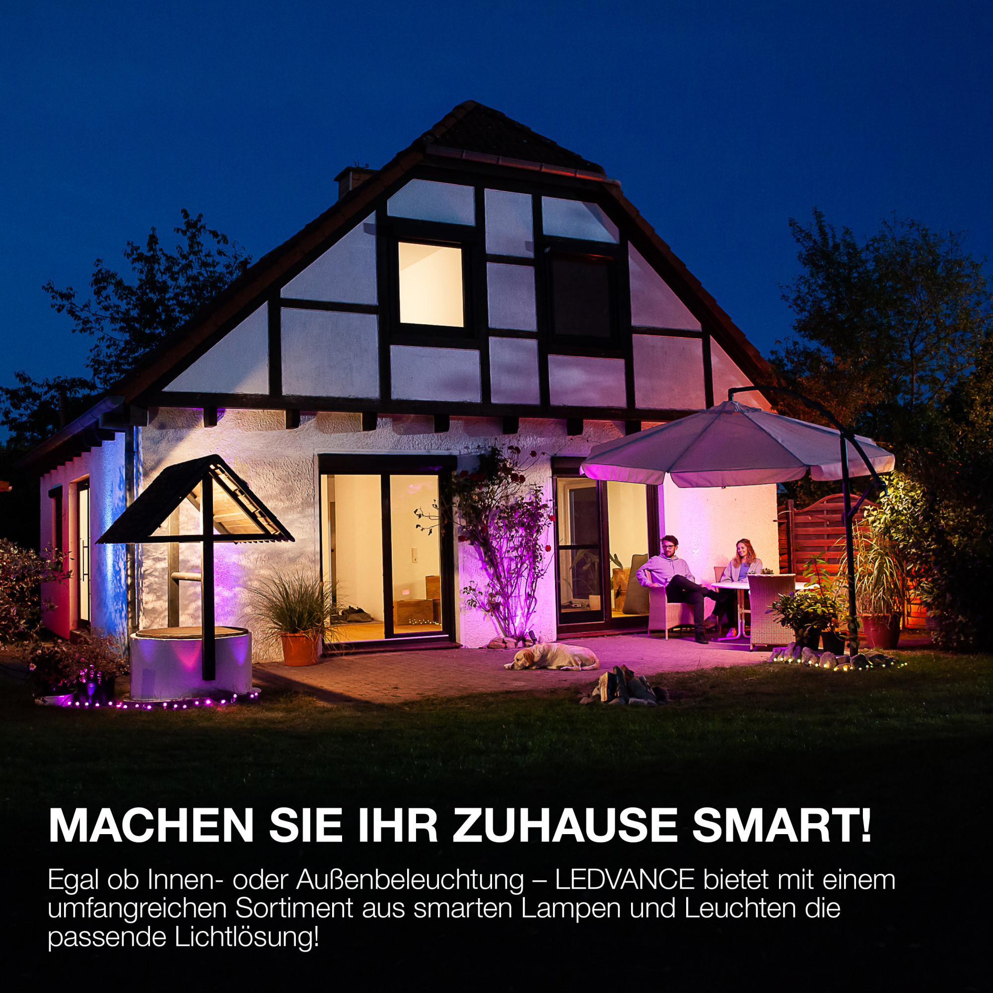 Ein Haus bei Nacht mit intelligenten Lichtern. Menschen sitzen auf der beleuchteten Terrasse.