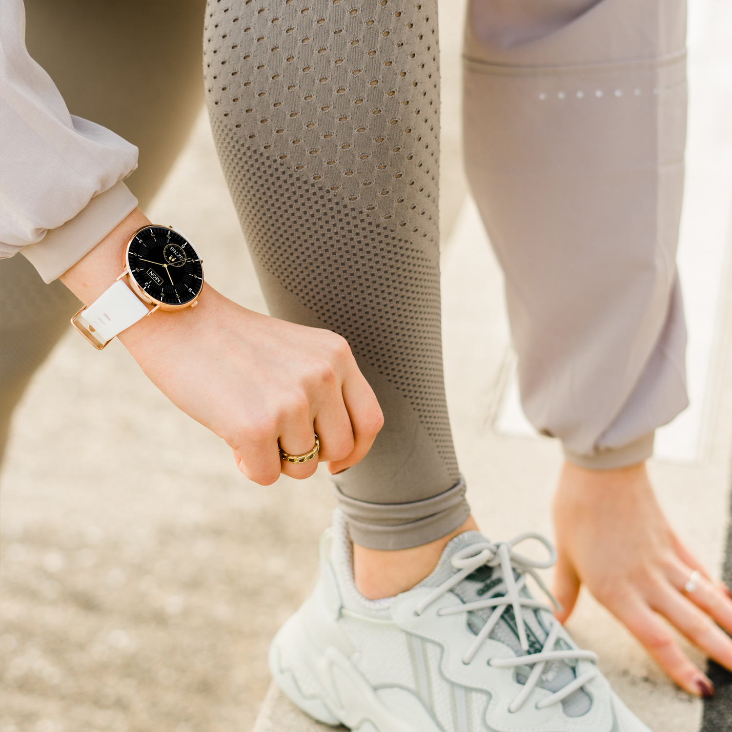 Eine Person, die eine Uhr am Handgelenk trägt, beugt sich und bereitet sich auf einen Lauf vor.