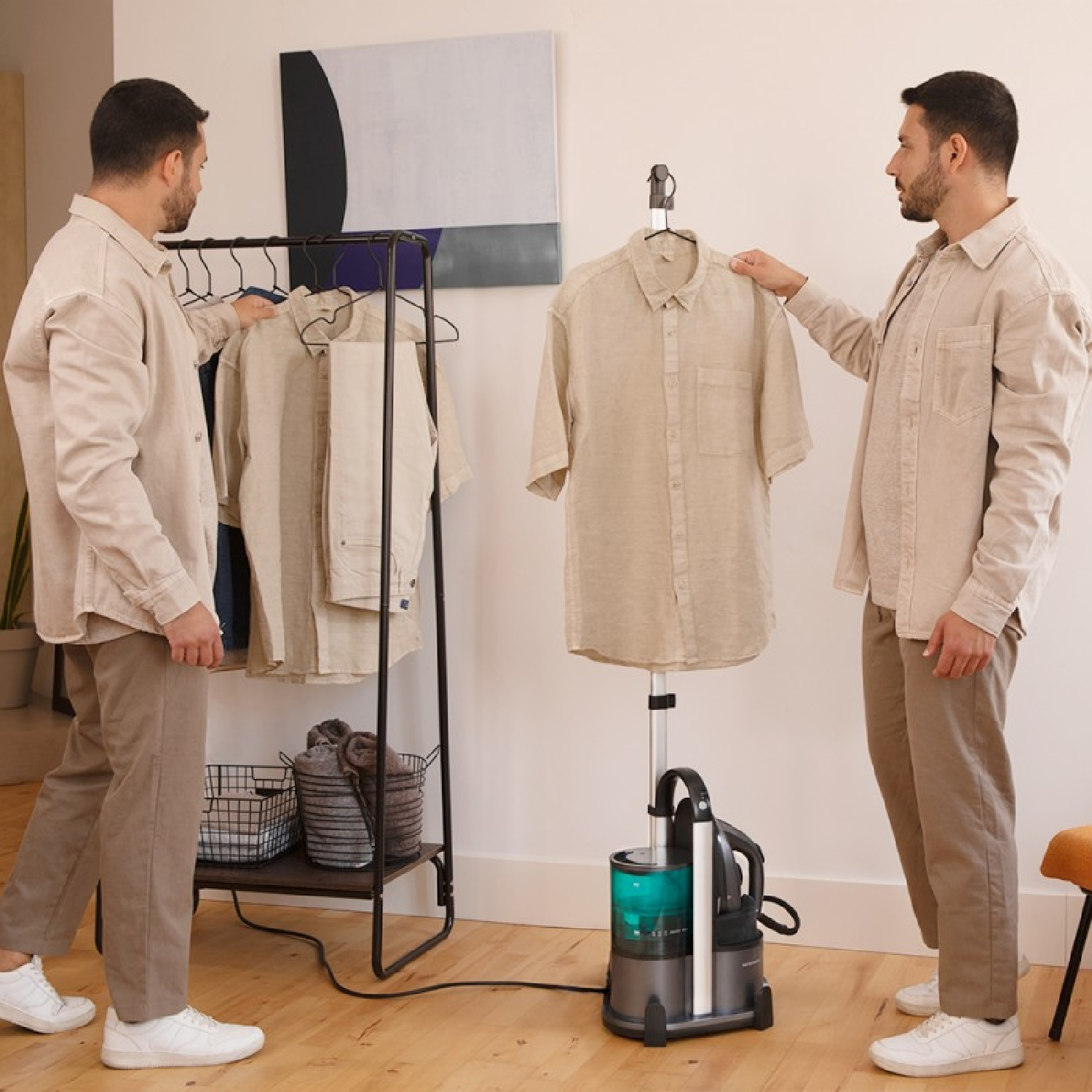 Two men with a clothes steamer, hanging a shirt on a rack with other clothes.