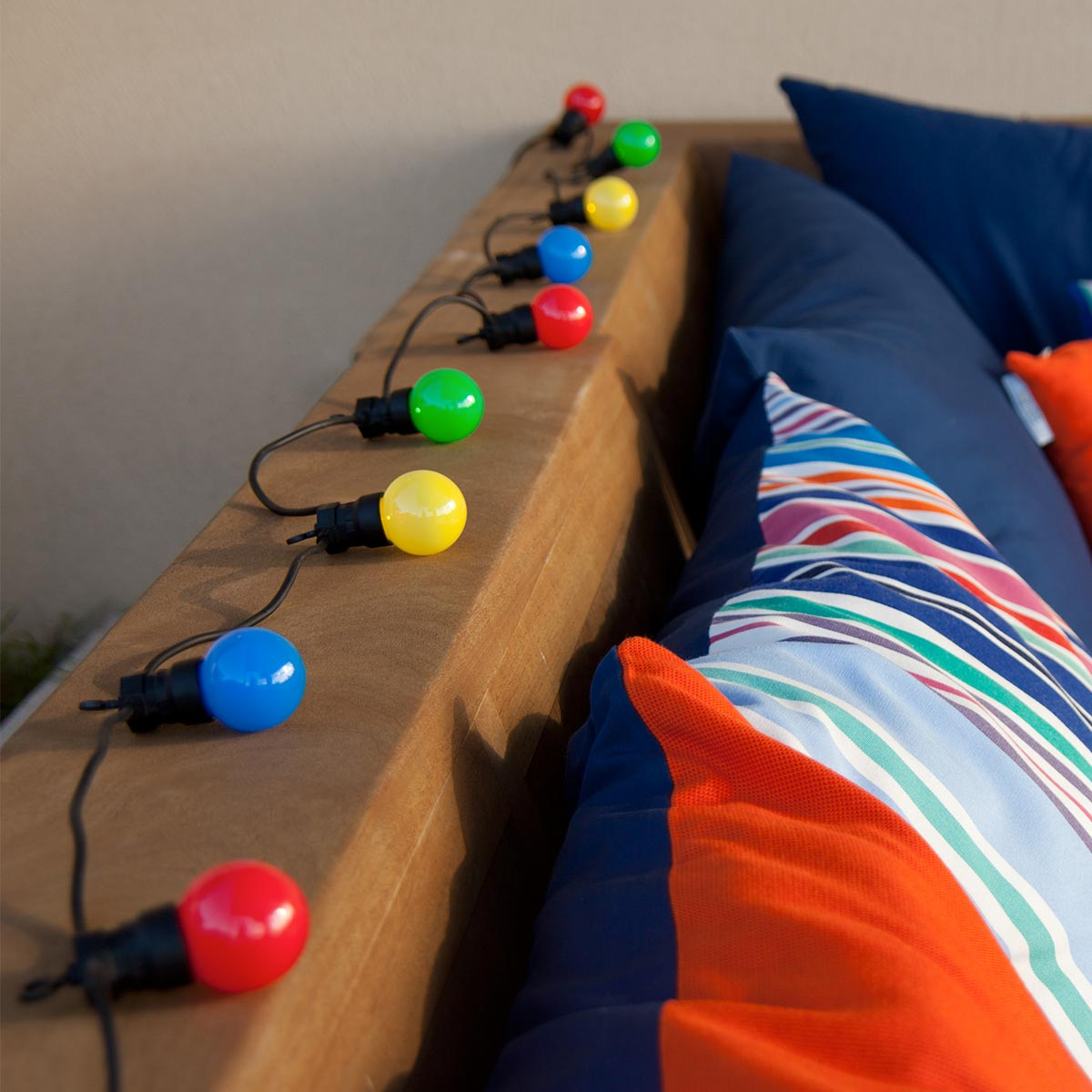 Lichterkette mit bunten Lichtern auf Holzoberfläche. Blaue, grüne, gelbe und rote Glühbirnen.