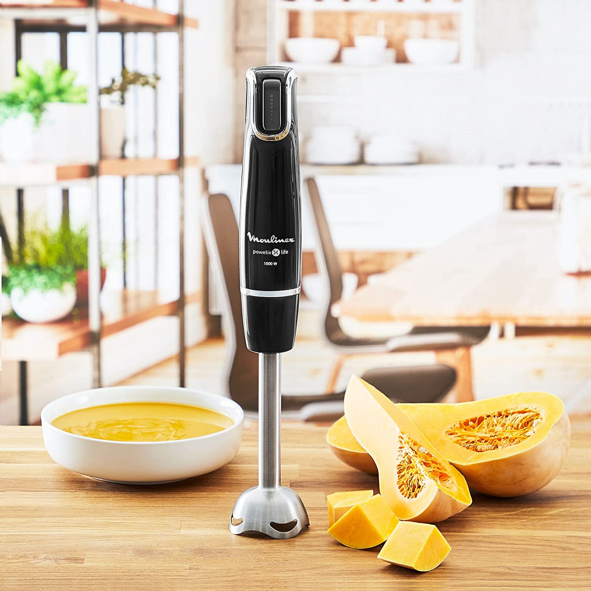 Czarny blender ręczny z miską zupy i dynią. Marka to Moulinex.