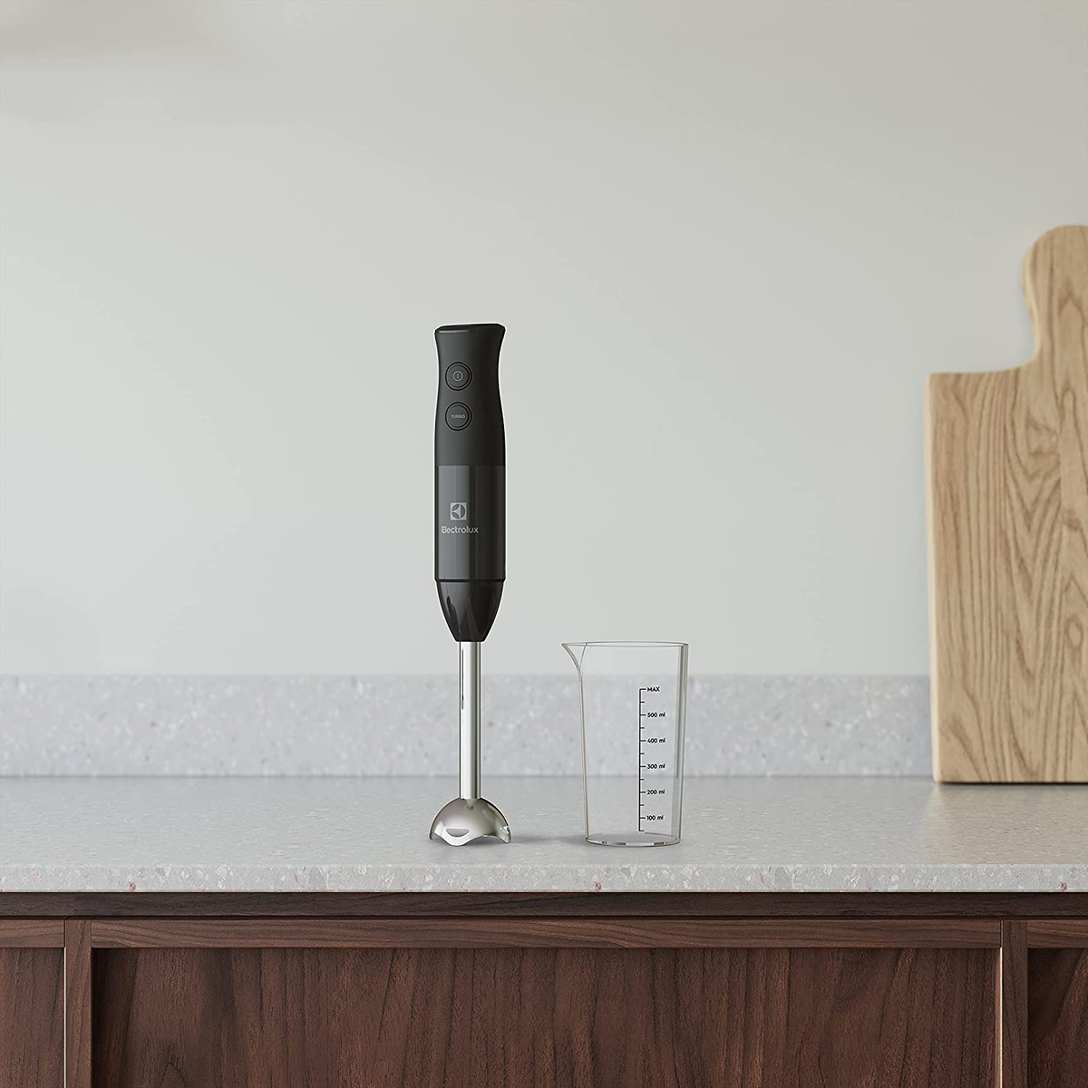 Czarny blender ręczny i miarka na drewnianym blacie, białe tło.