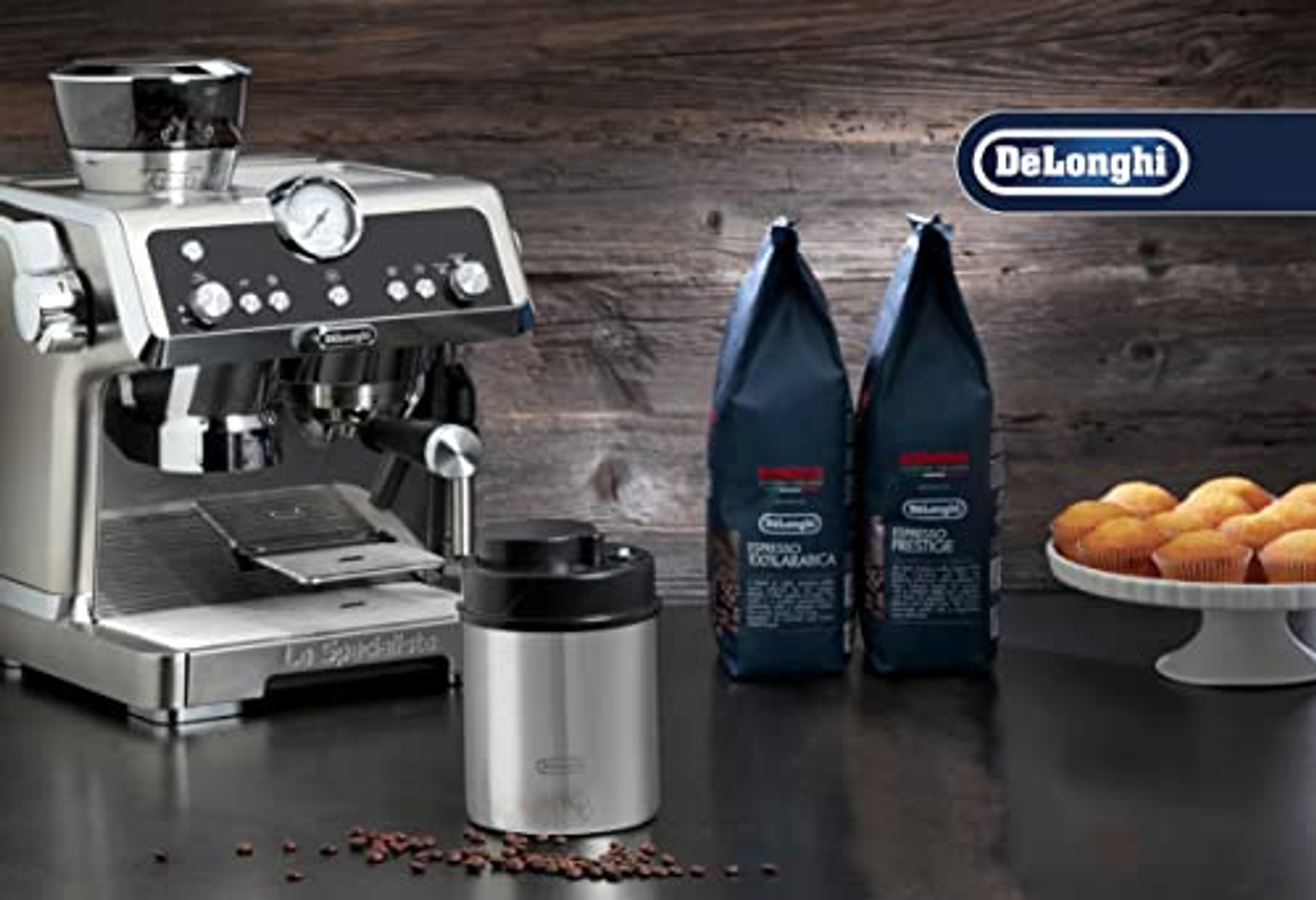 Kaffeemaschine mit Kaffeebohnen und einem Behälter, Muffins auf einem Teller. DeLonghi Logo.