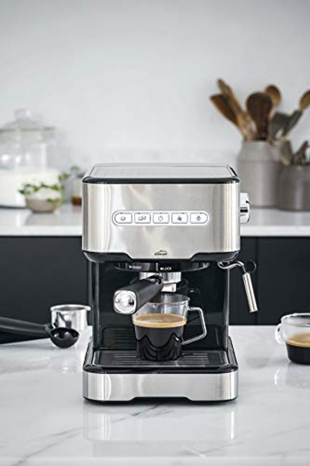 Máquina de espresso con una taza de café. Cocina al fondo.