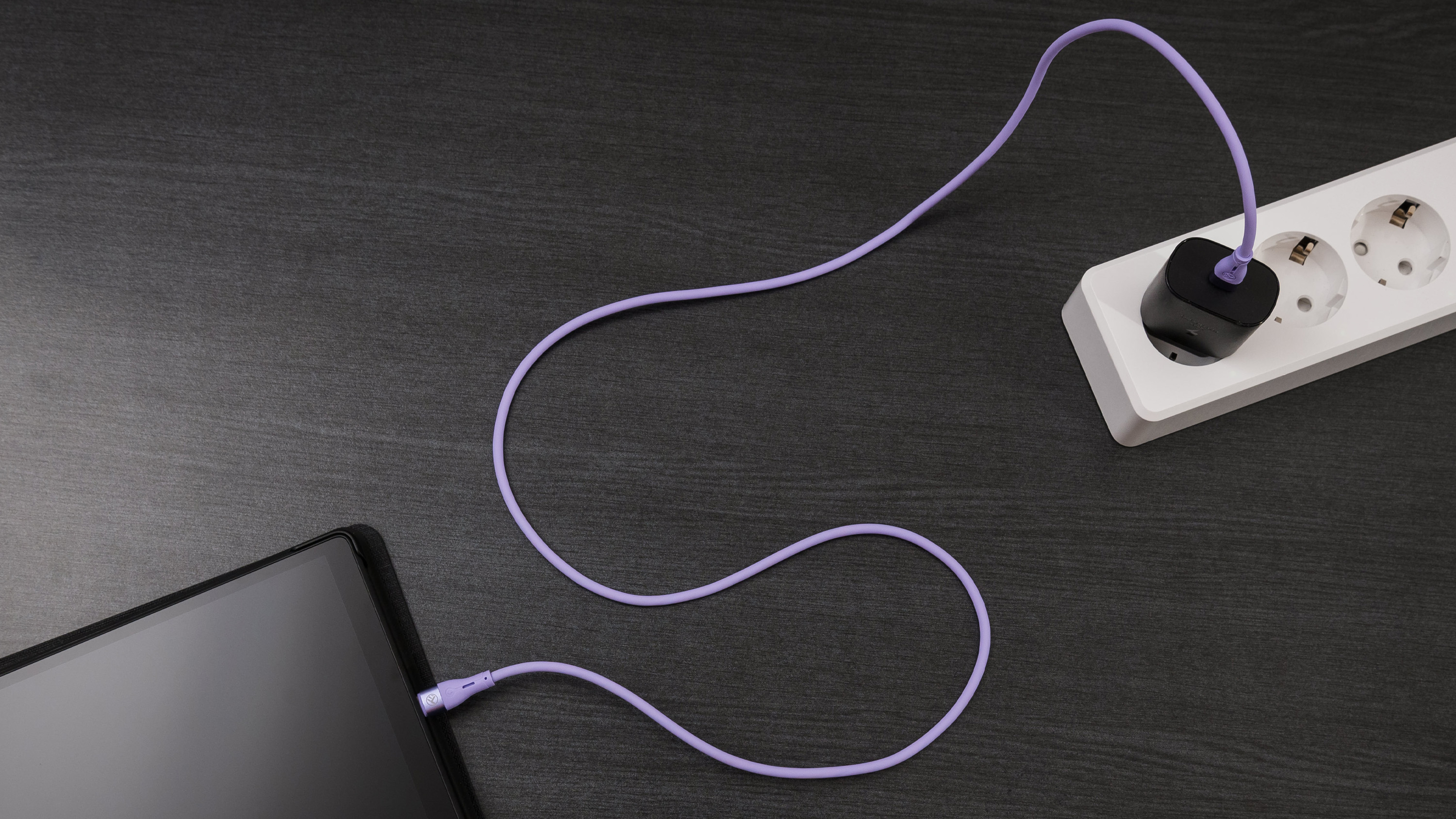 Tablet ładuje się za pomocą fioletowego kabla. Kabel jest podłączony do listwy zasilającej.