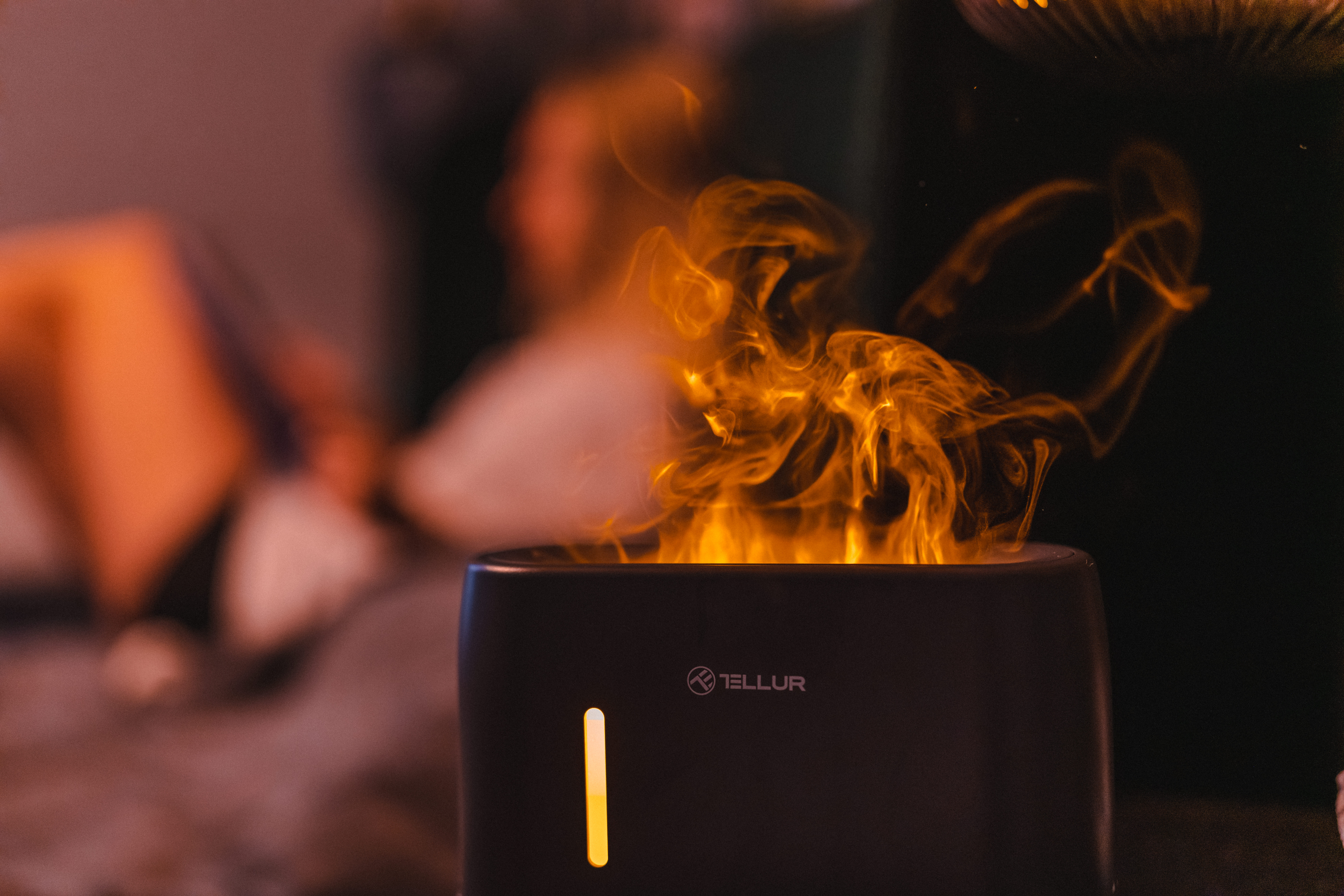 Czarny oczyszczacz powietrza z pomarańczowym efektem płomienia i logo Tellur.