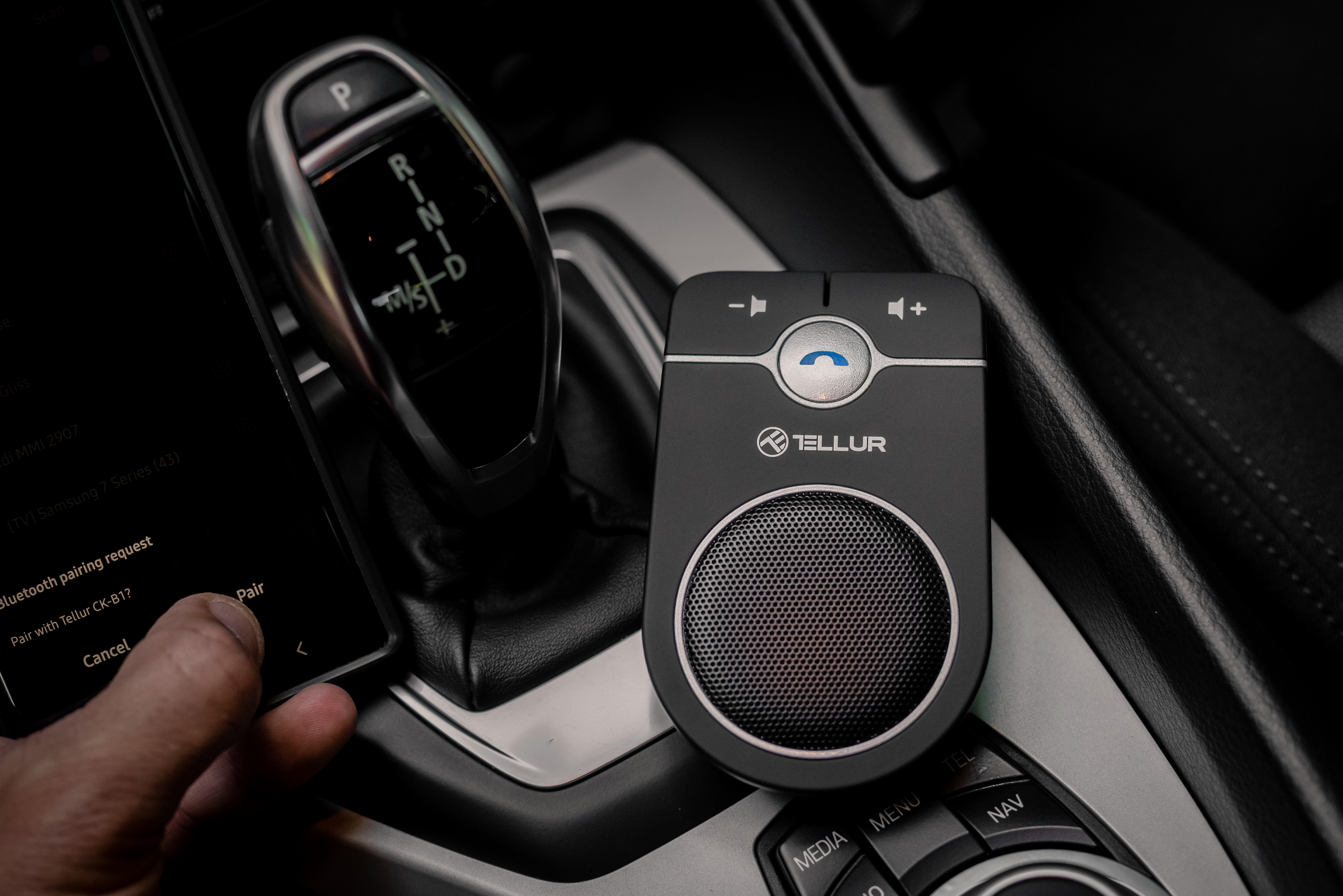 Un altavoz Tellur negro y un teléfono que muestra una solicitud de emparejamiento en el interior de un coche.