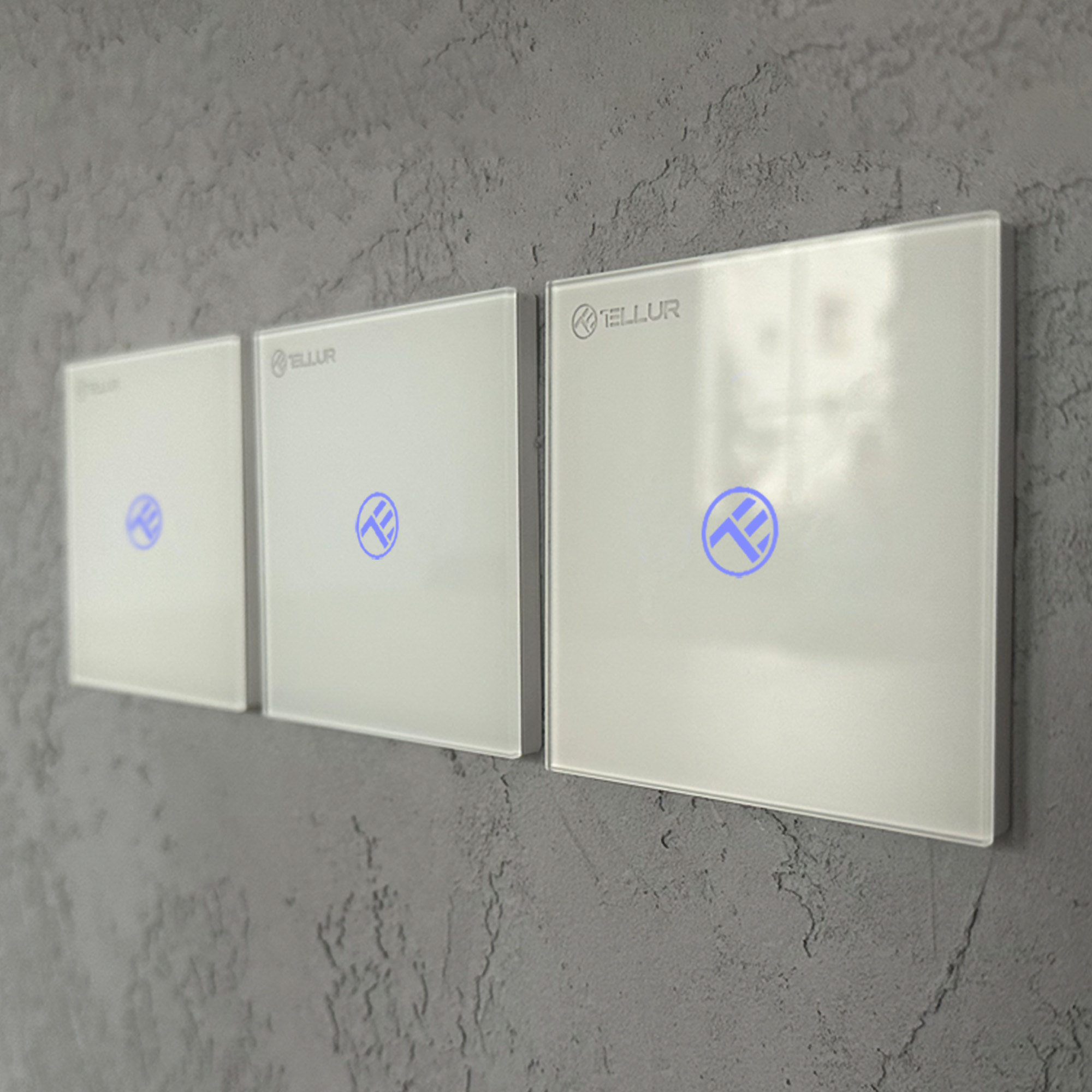 Tres interruptores de luz inteligentes blancos con círculos azules iluminados. Montados en una pared gris texturizada. Diseño simple.