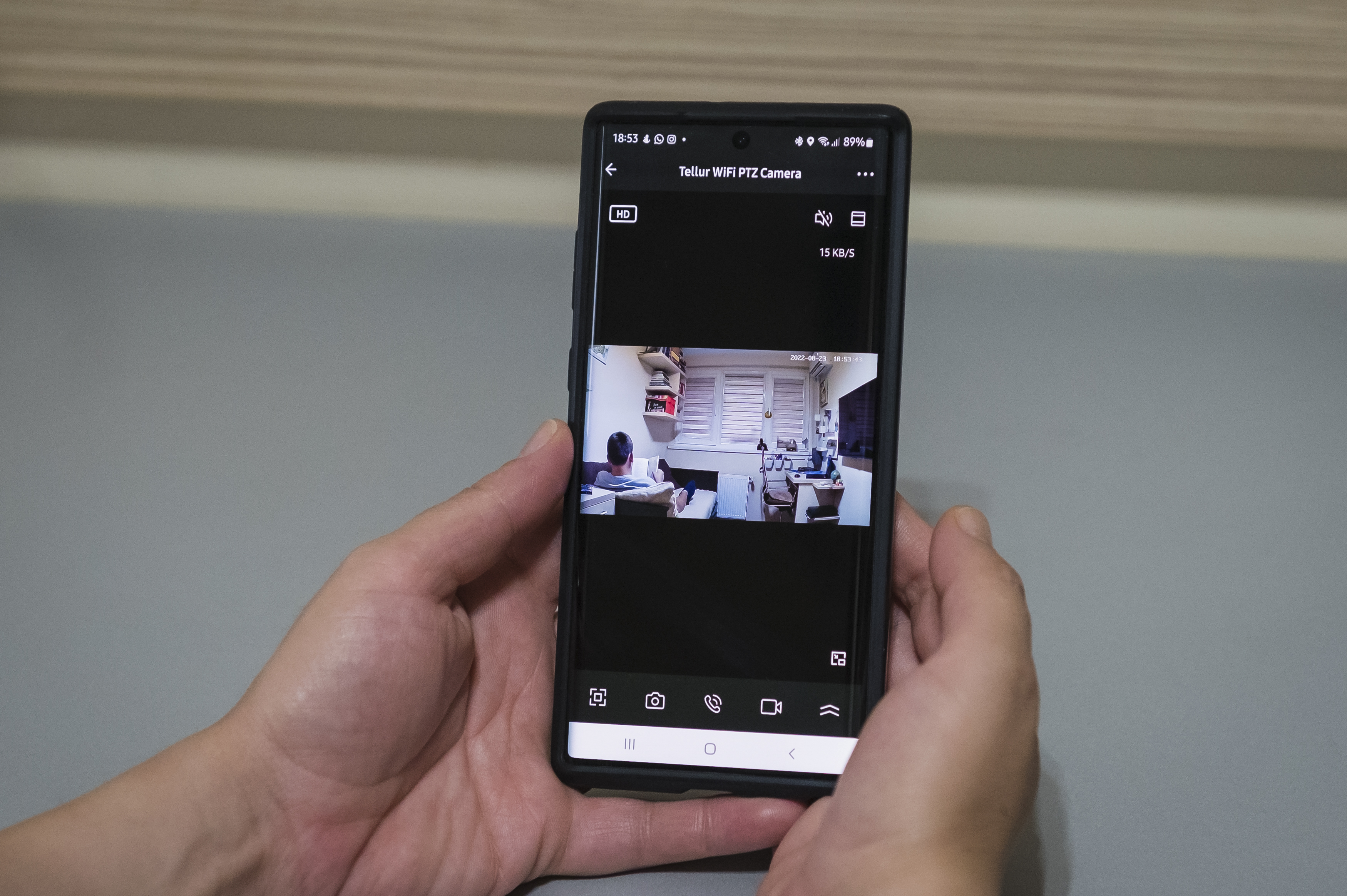 Osoba trzymająca smartfona wyświetlającego transmisję wideo na żywo z kamery.