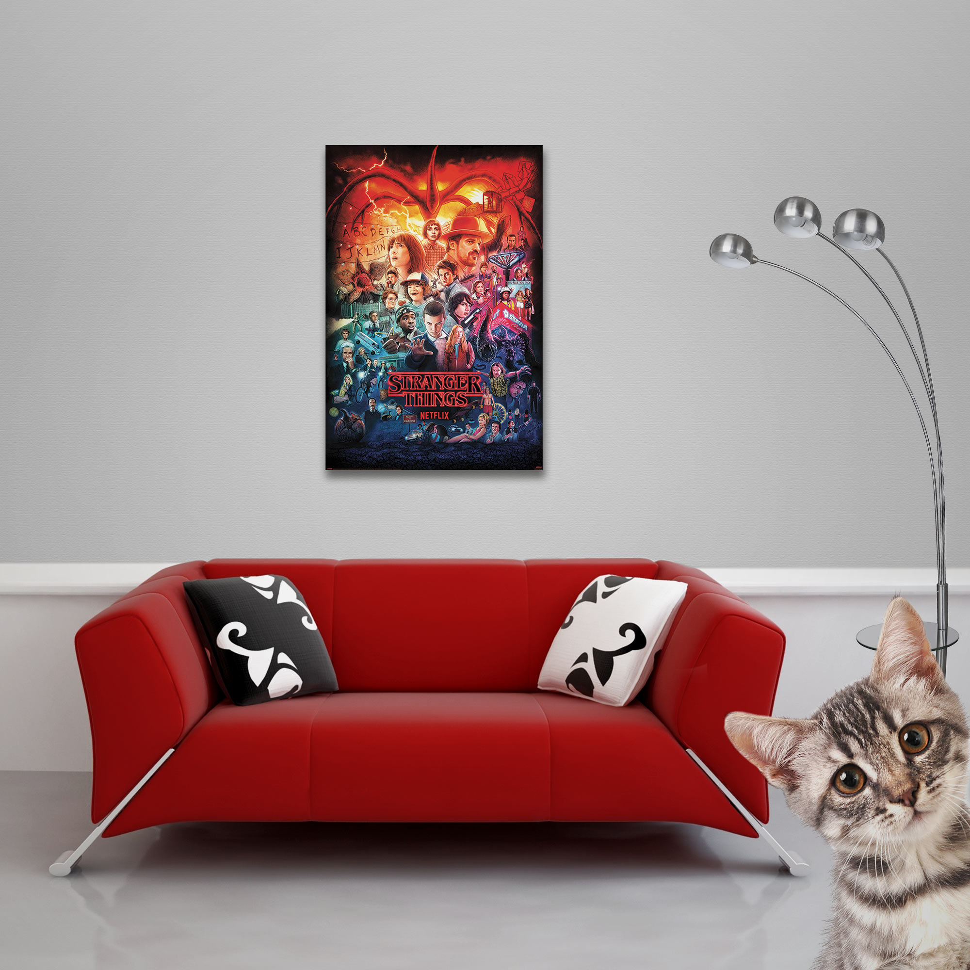Ein Wohnzimmer mit rotem Sofa, Poster und Katze, die in die Kamera schaut.