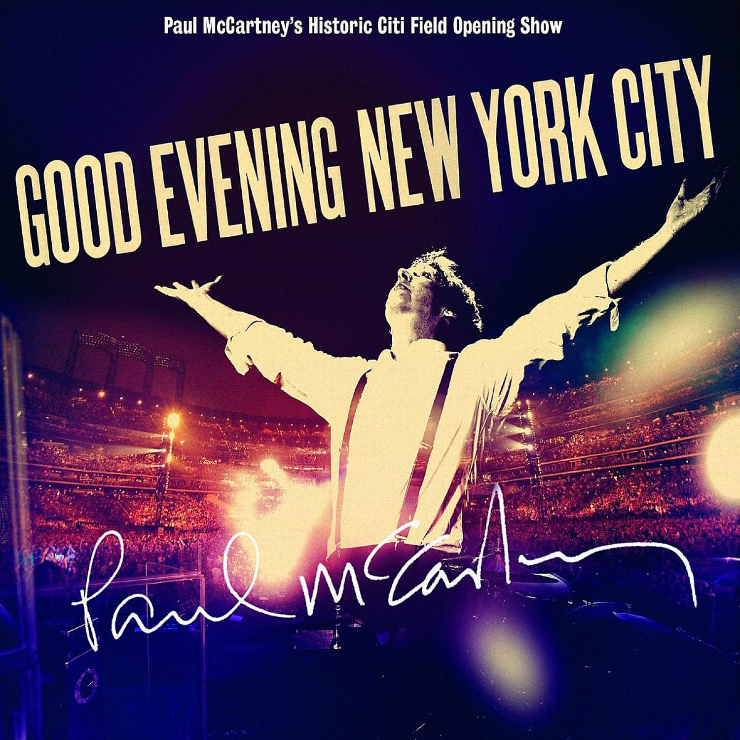 Paul McCartney auf der Bühne mit ausgestreckten Armen, Publikum im Hintergrund. Text: Good Evening New York City.