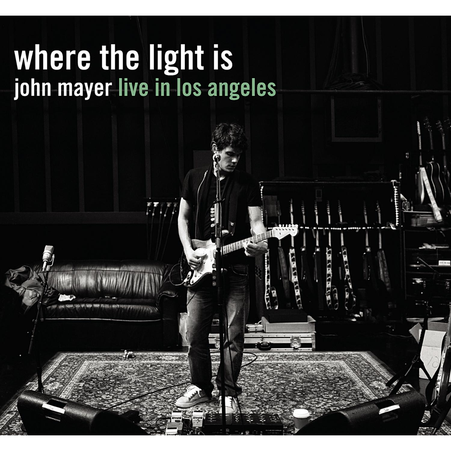 John Mayer spielt Gitarre auf der Bühne. Ein Mikrofon und Gitarren im Hintergrund. Der Titel 'Where The Light Is'.