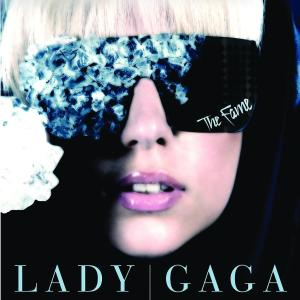 Lady Gaga trägt eine Sonnenbrille, die ihre Augen bedeckt. Es steht The Fame drauf. Schwarzer Hintergrund.