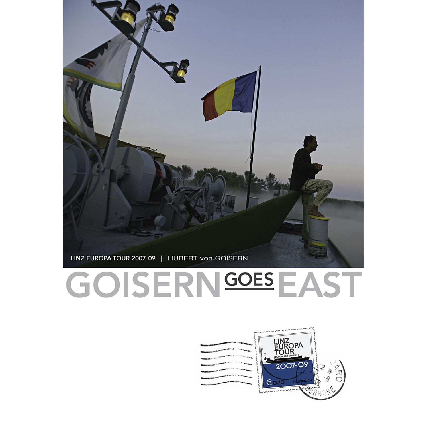 Ein Boot auf einem Fluss mit Flagge, ein Mann sitzt auf dem Boot. Text: Goisern Goes East.