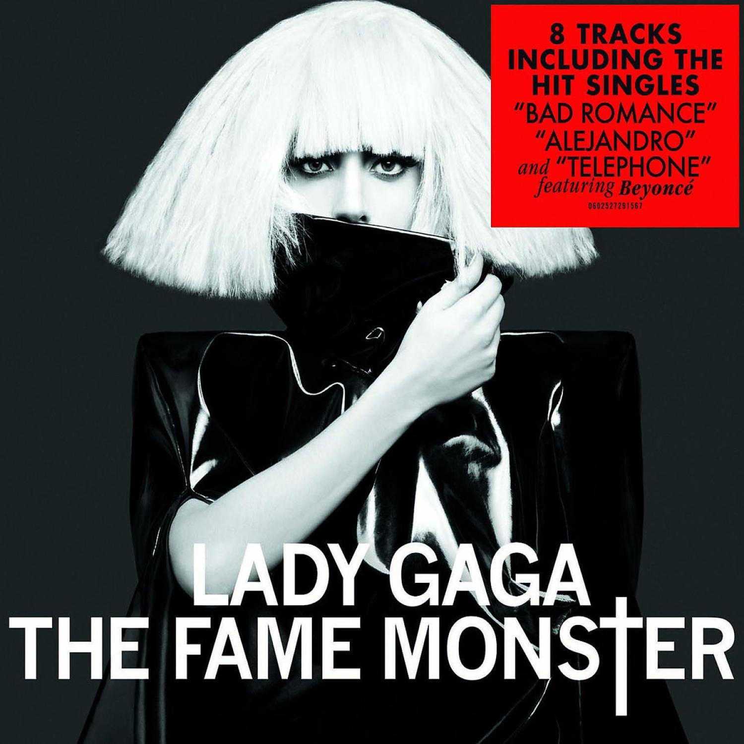 Lady Gaga albumhoes. Ze houdt een zwart kledingstuk vast. Een rode doos heeft albumdetails.