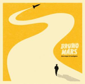 Albumcover: Ein Mann geht auf der hellgelben Straße auf eine Flugzeugsilhouette zu. Wörter "Bruno Mars" und Albumtitel.
