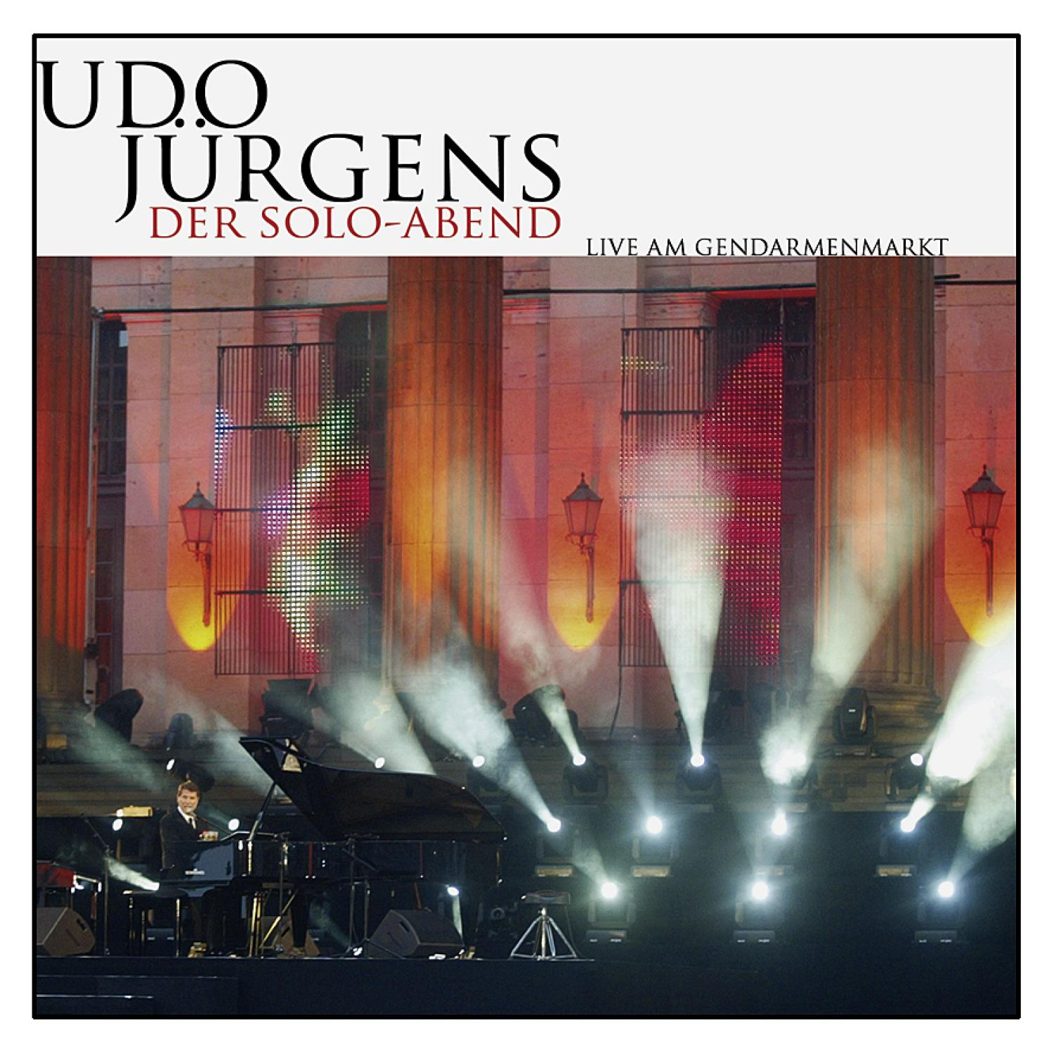 Bühne mit Lichtern, Udo Jürgens spielt Klavier und singt. Große Säulen im Hintergrund.
