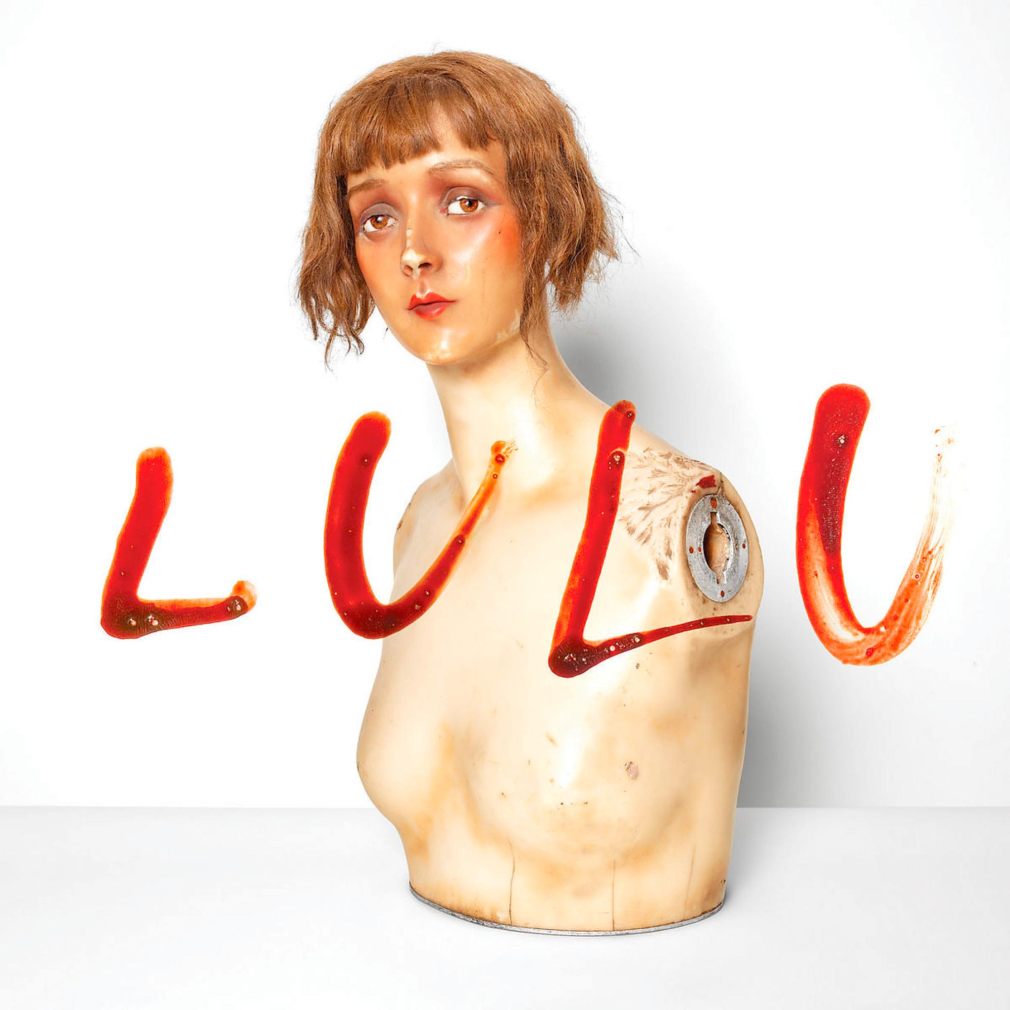 Un torse de mannequin avec des éclaboussures de liquide rouge formant le mot LULU. Le fond est blanc.