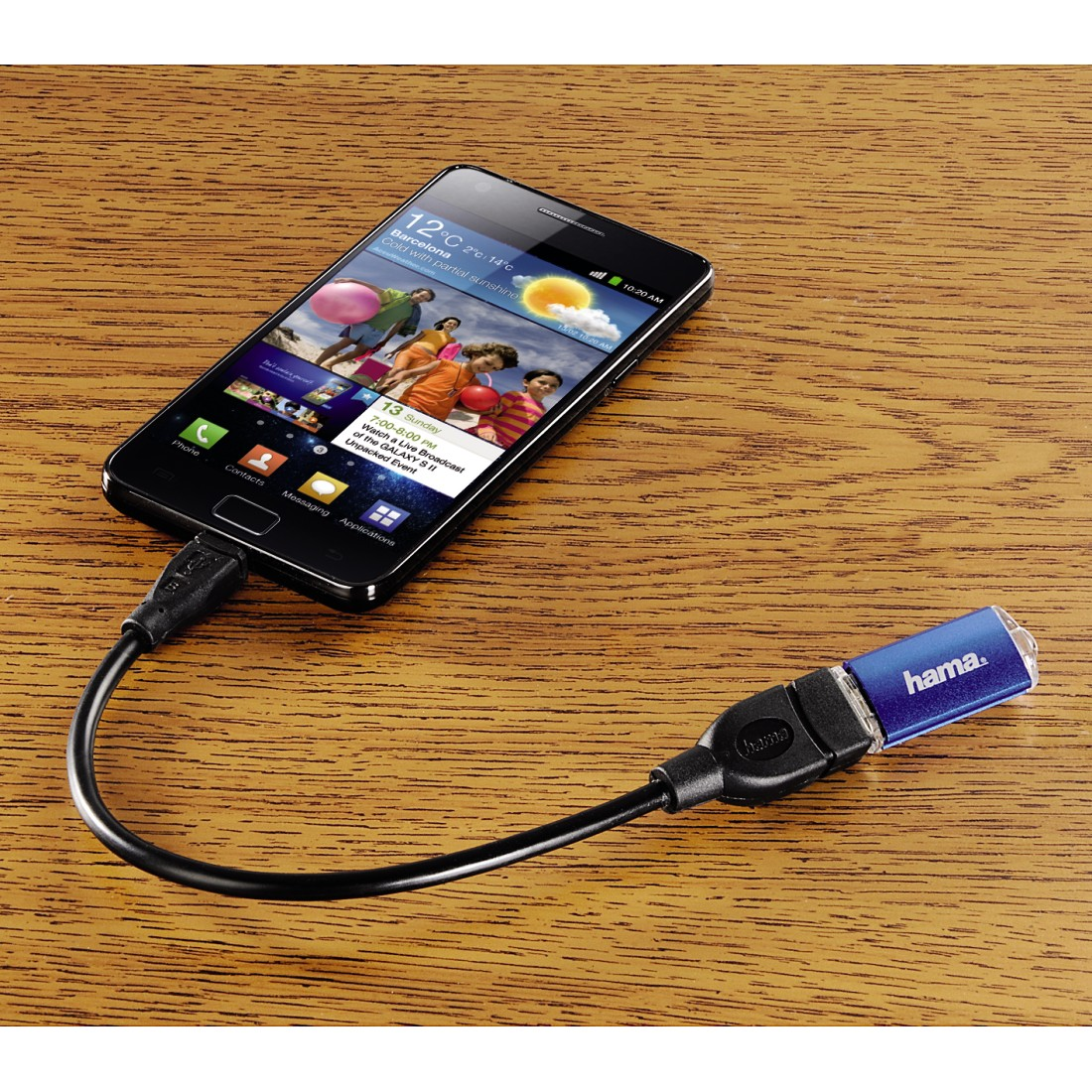 Okostelefon USB-meghajtóhoz csatlakoztatva, fa felületen, a telefonon egy felület látható.