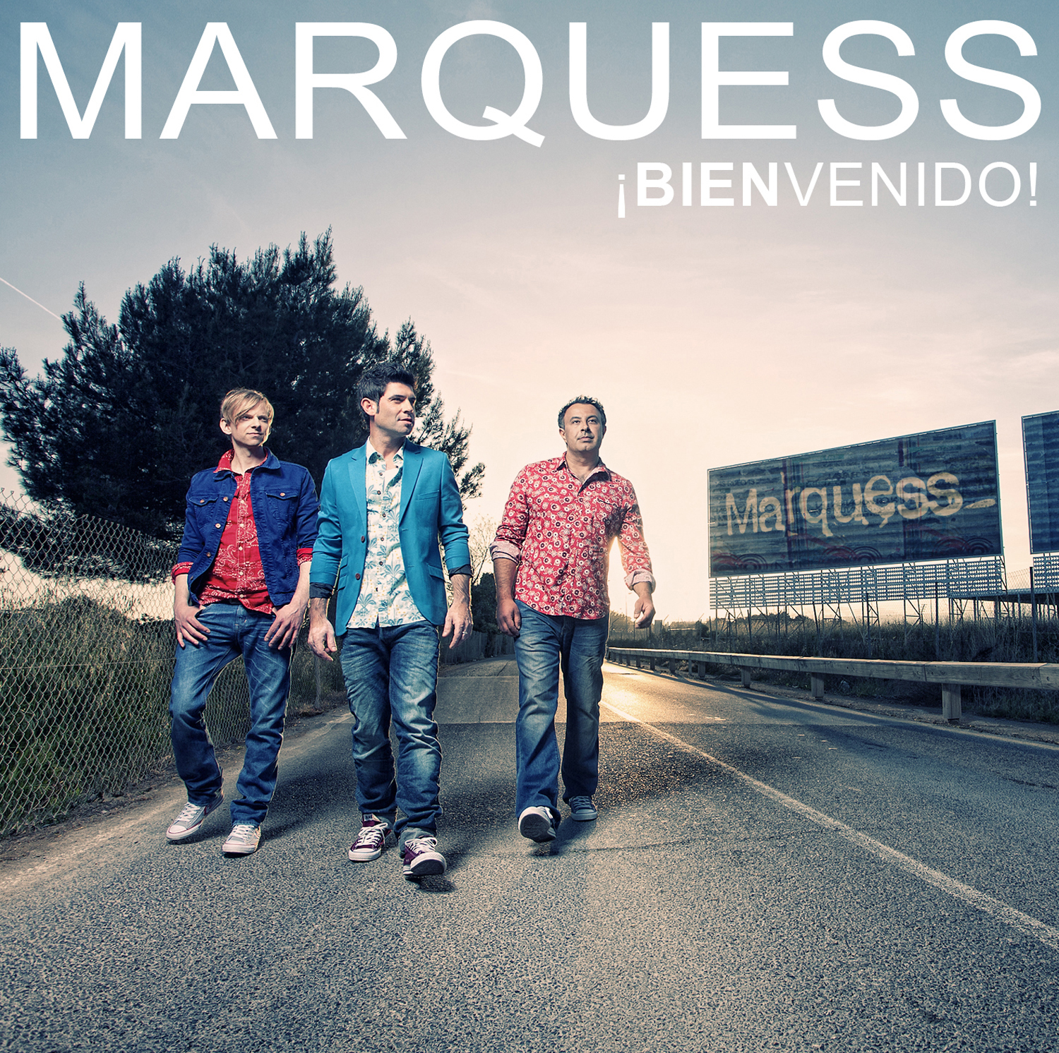 Drei Männer gehen auf einer Straße, Text 'Marquess, ¡BIENVENIDO!'.