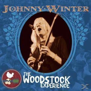 Johnny Winter auf der Bühne, singt und spielt Gitarre, in blauem Rahmen.
