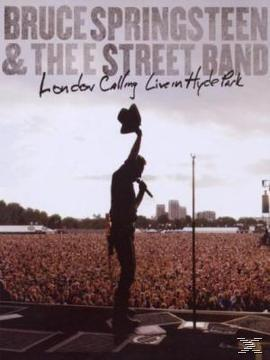 Bruce Springsteen live auf der Bühne, hält einen Hut. Publikum und Bühne sind im Hintergrund.