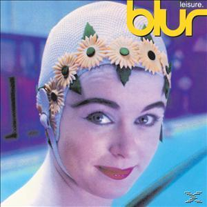 Frau mit floralem Badehut, lächelnd. Der Hintergrund ist ein blaues, verschwommenes Schwimmbad.