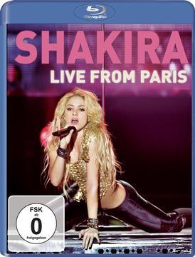 Shakira auf der Bühne, singt in ein Mikrofon, rosa Hintergrund, Text.