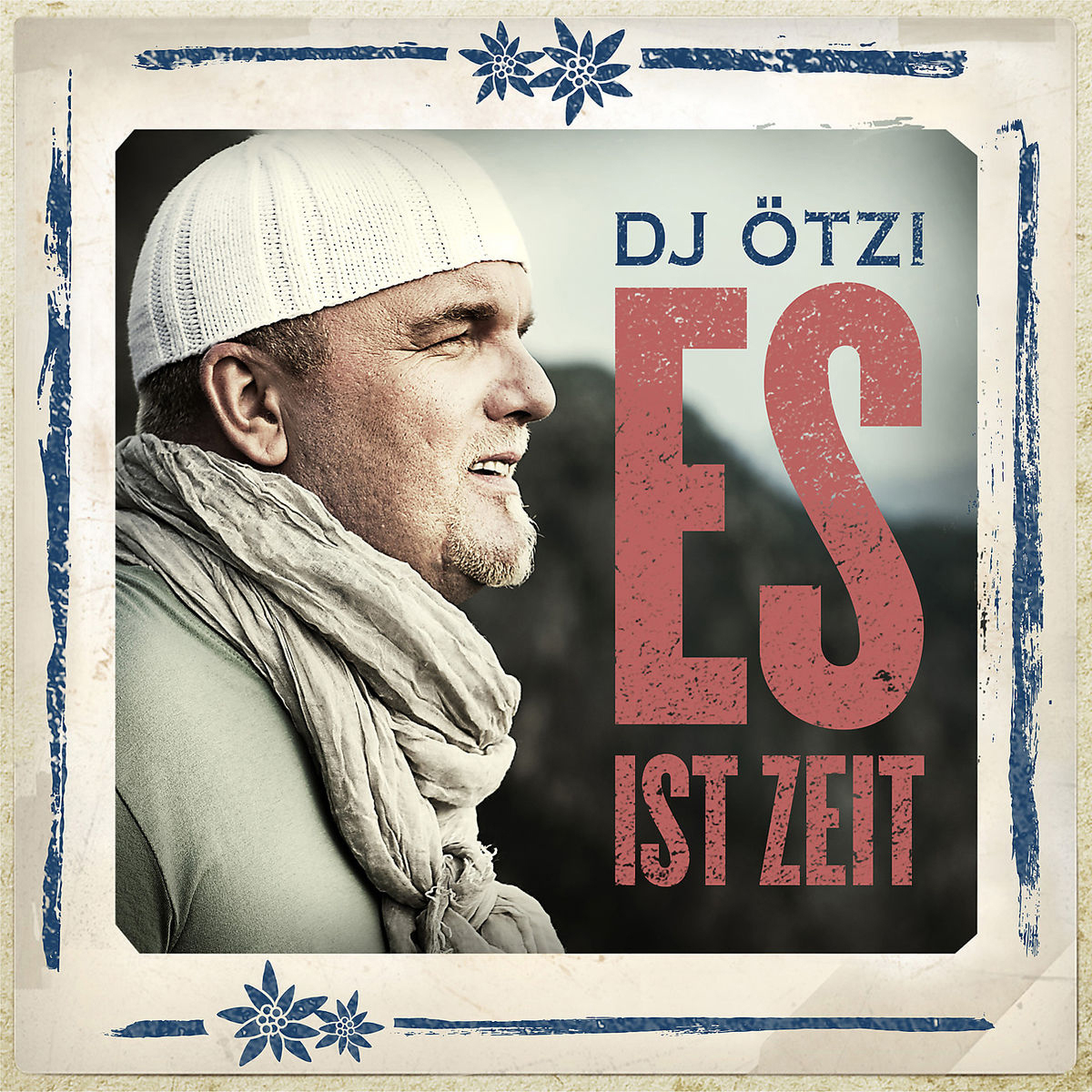 Mann mit weißem Hut, Schal und grünem Hemd. Der Text "ES IST ZEIT" ist sichtbar.