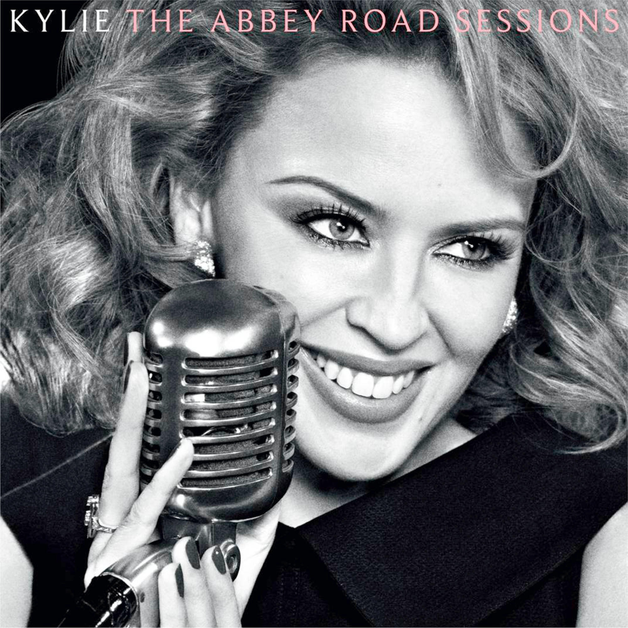 Kylie Minogue, die ein Mikrofon hält und lächelt, mit einem Mikrofon in der Hand.