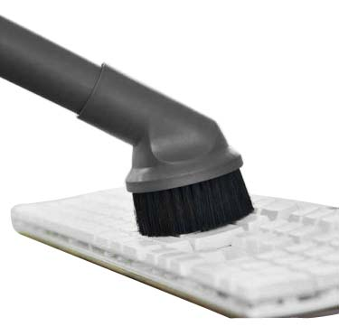 Eine Staubsaugerbürste, die eine weiße Tastatur reinigt.
