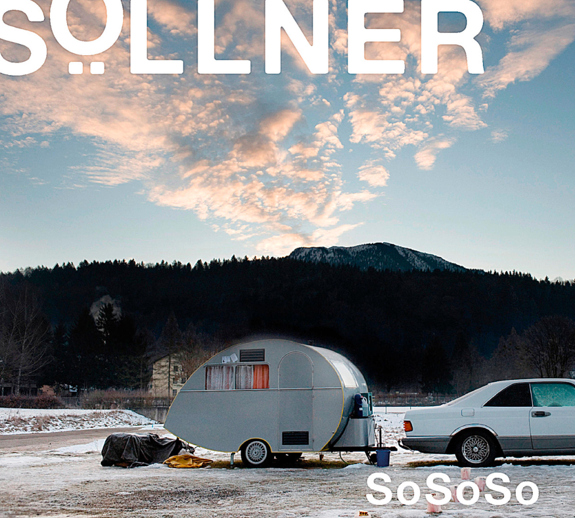 Szene: Wohnwagen und Auto, Schnee auf dem Boden, Berge und Himmel, Sollner Text.